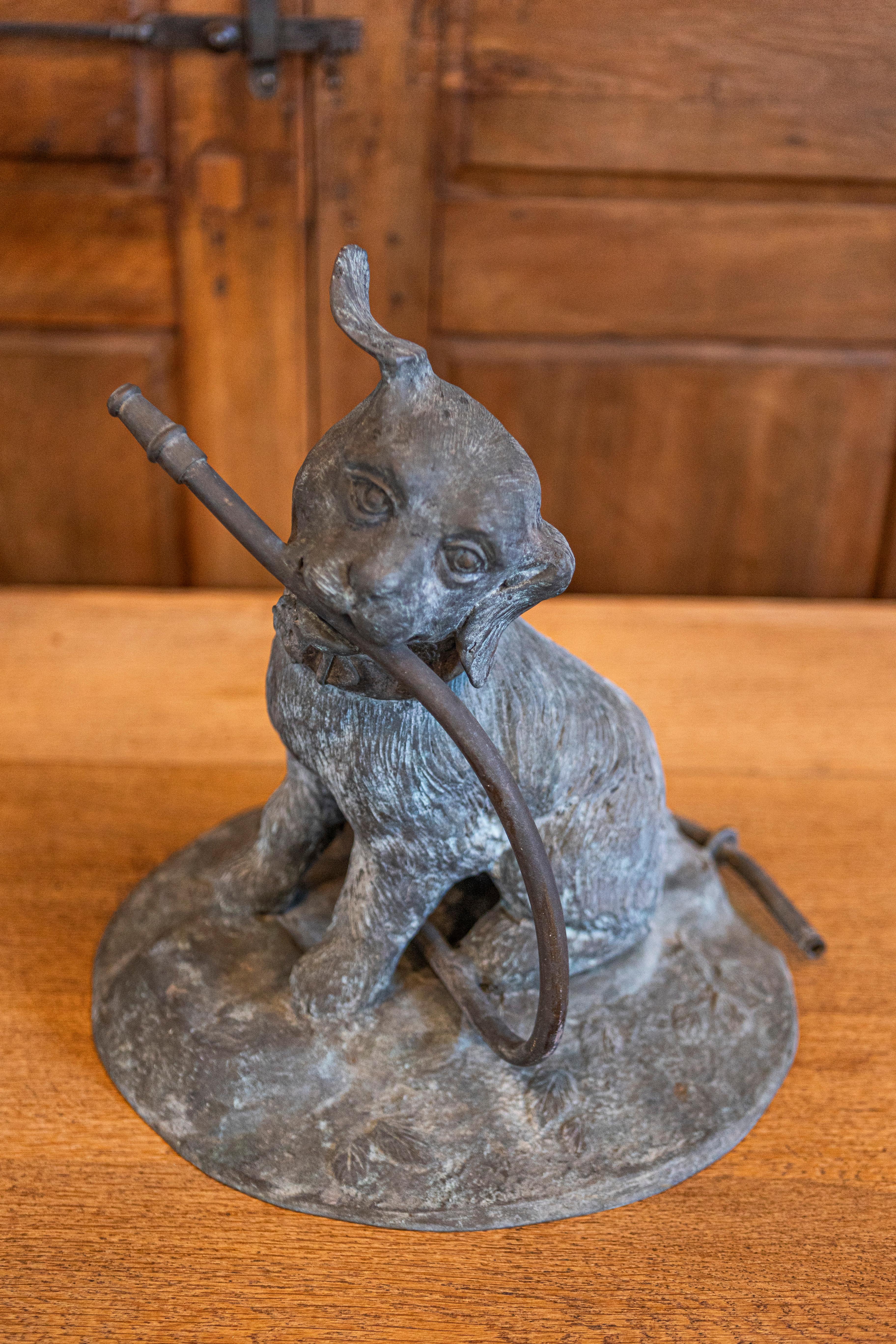 A French bronze dog fountain from the early 20th century. This charming early 20th-century French bronze dog fountain captures a delightful and playful spirit, ideal for enhancing a garden or courtyard. The statue portrays a dog, head tilted to the