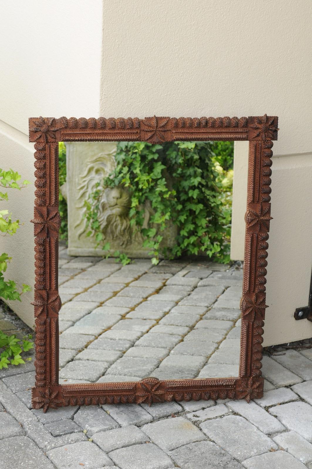 A French hand carved Tramp Art wall mirror from the early 20th century, with star motifs. Born in France during the turn of the century, this handsome wooden mirror presents the stylistic characteristics typical of the Tramp Art style. A simple,