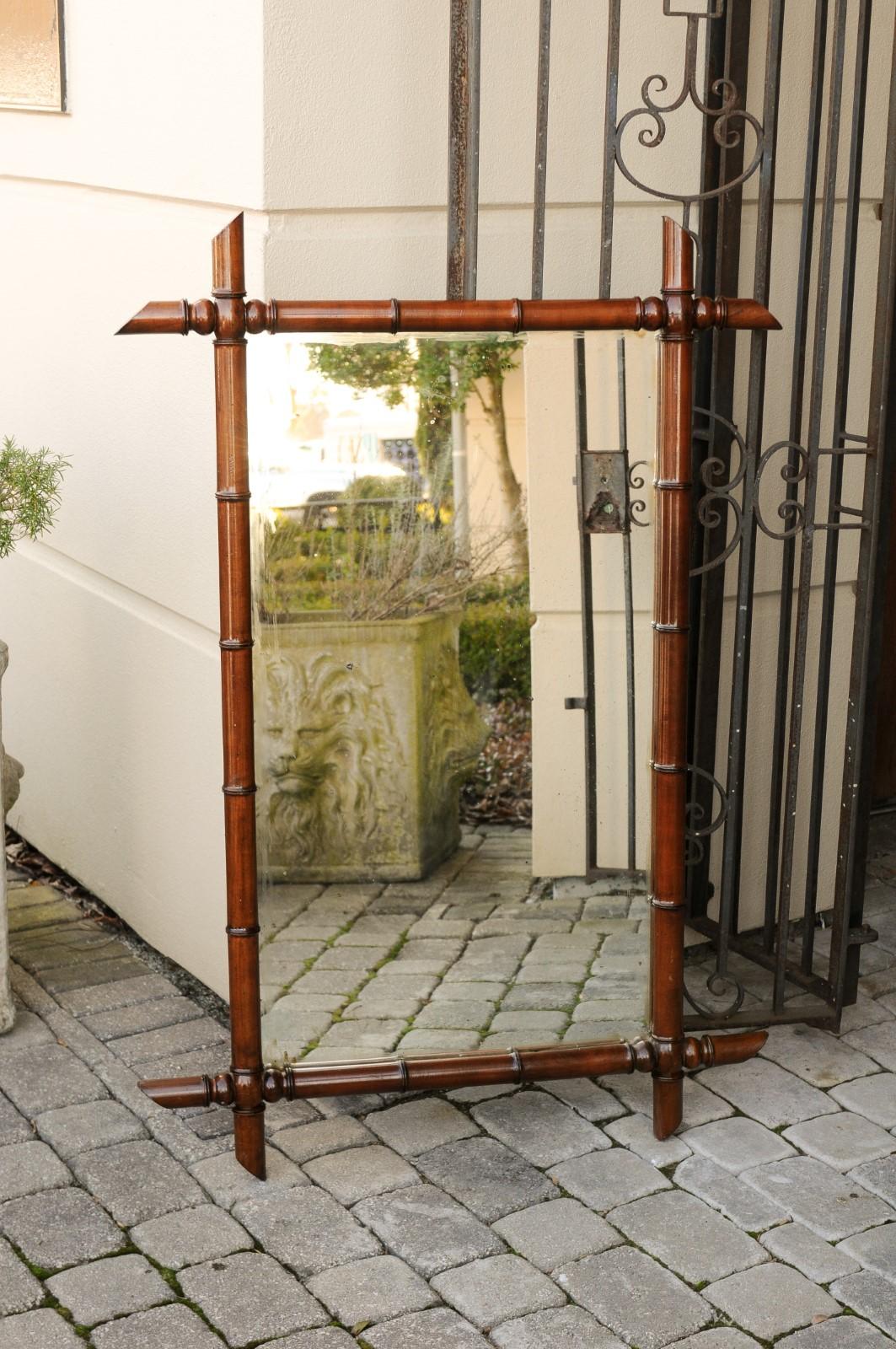 A French faux-bamboo rectangular mirror from the early 20th century, with brown patina and protruding corners. Born in France at the turn of the century (19th to 20th), this handsome mirror features a linear silhouette presenting a brown faux bamboo