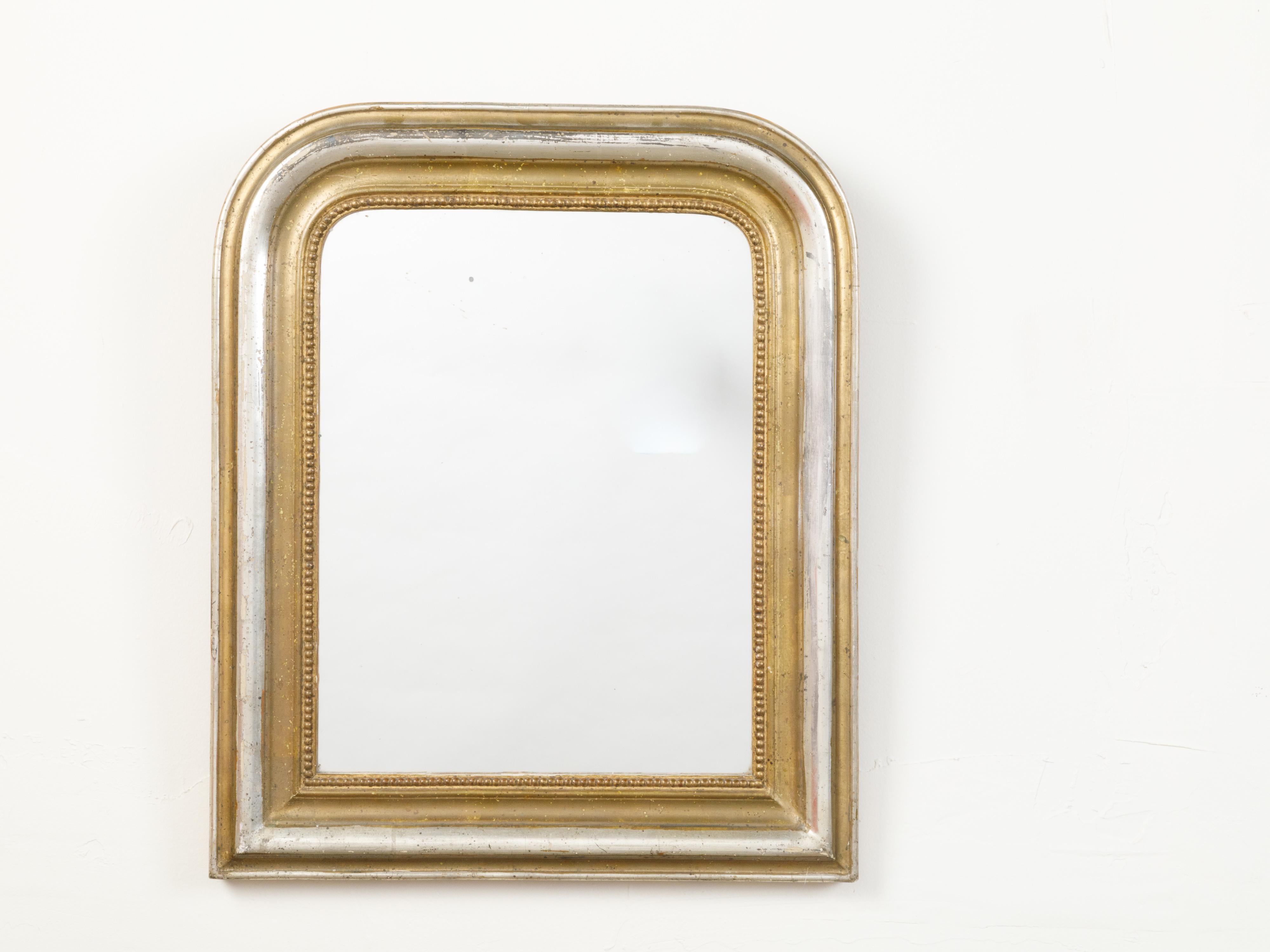A French Louis-Philippe style mirror from the early 20th century, with silver and gold tones. Created in France at the Turn of the Century, this mirror features the typical Louis-Philippe silhouette accented with rounded corners at the top.
