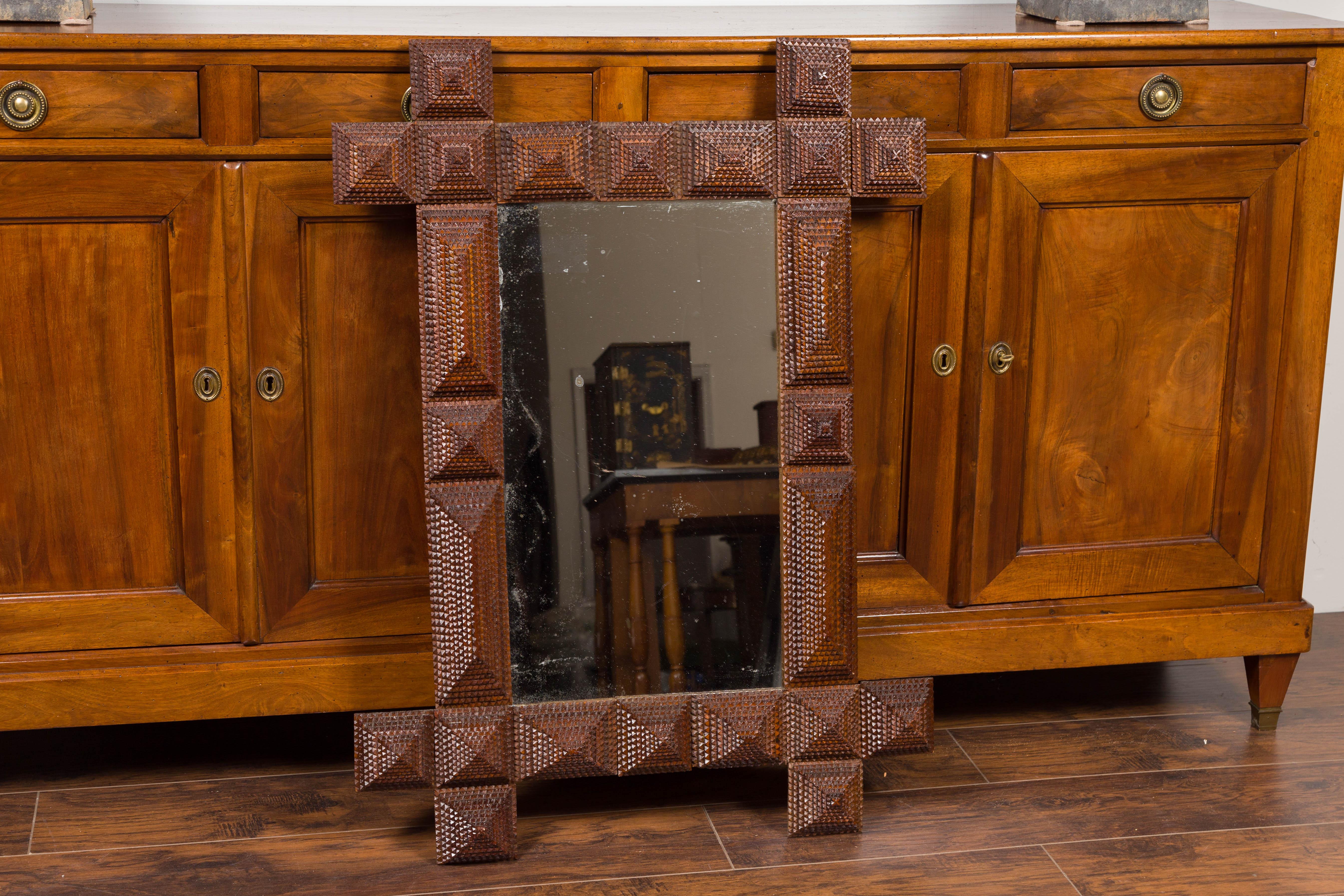 A French Tramp Art hand carved mirror from the early 20th century with raised pyramidal motifs and intersecting corners. Born in France during the early years of the 20th century, this French mirror was hand carved in the manner typical of the Tramp