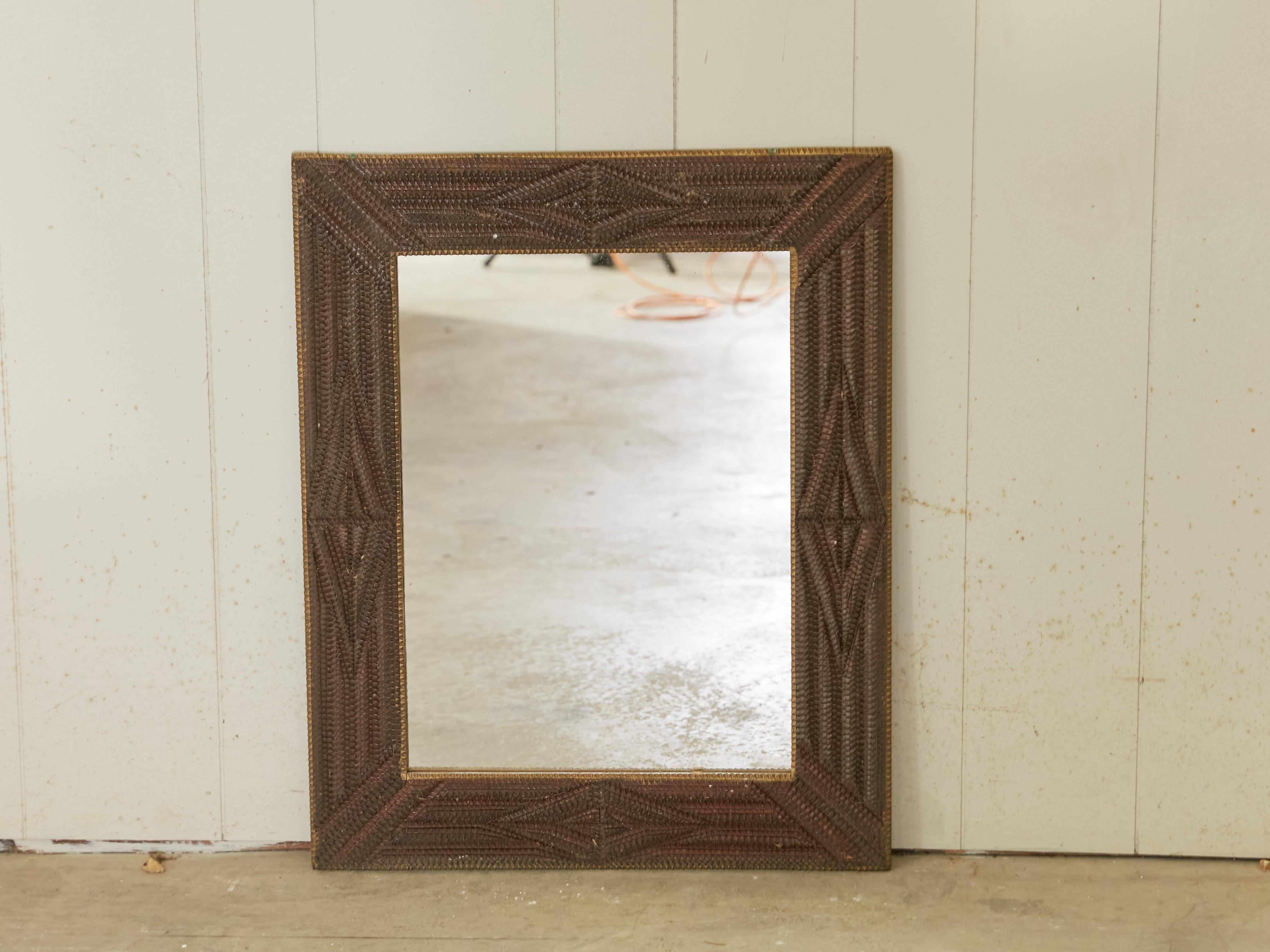 A French rectangular Tramp Art hand-carved wooden mirror from the early 20th century, with raised diamond motifs and geometric patterns. Created in France during the early years of the 20th century, this wall mirror was hand carved in the manner