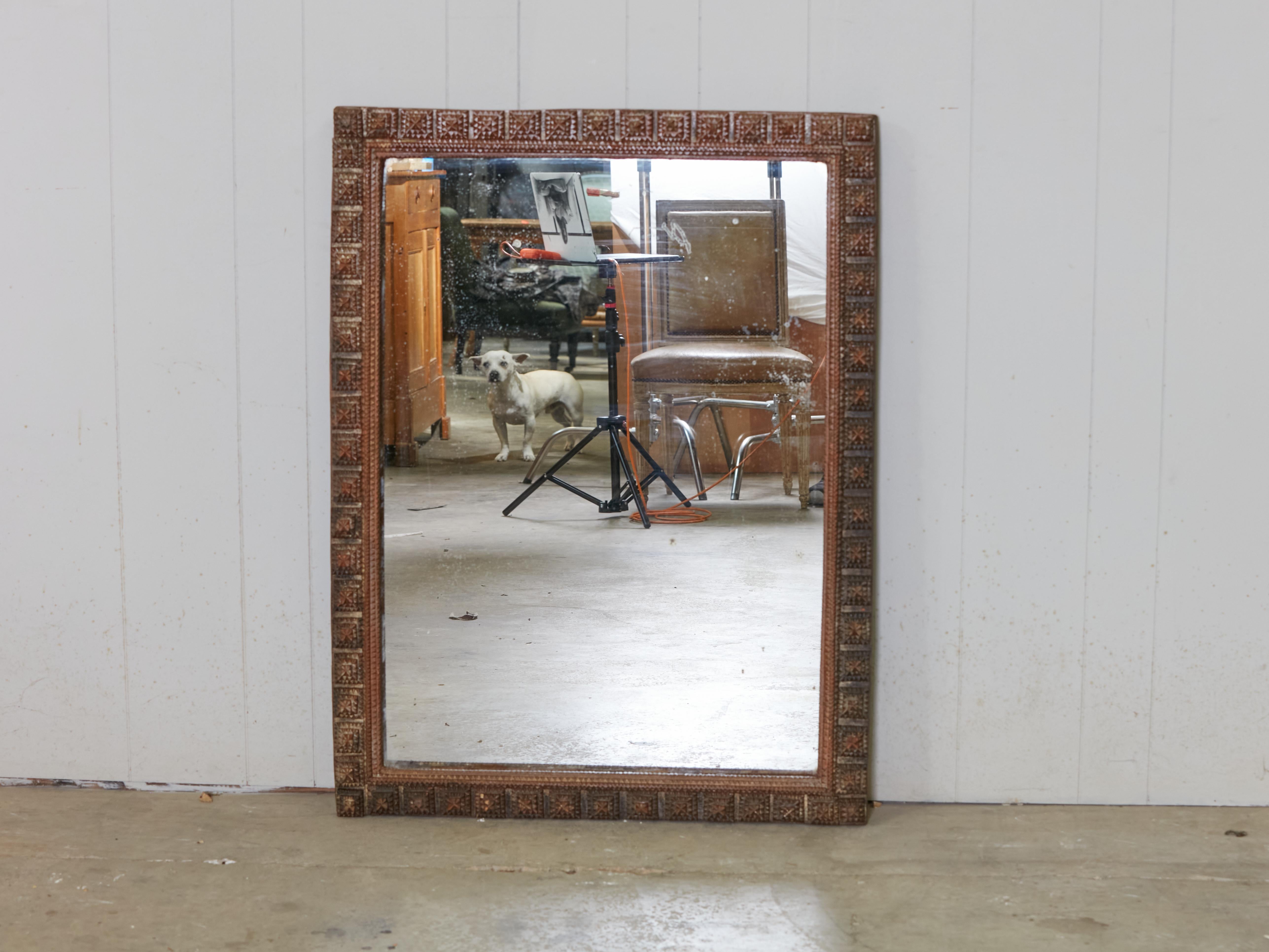 A French rectangular Tramp Art hand-carved wooden mirror from the early 20th century, with raised pyramidal motifs. Created in France at the turn of the century which saw the transition between the 19th to the 20th, in the typical folk Tramp Art