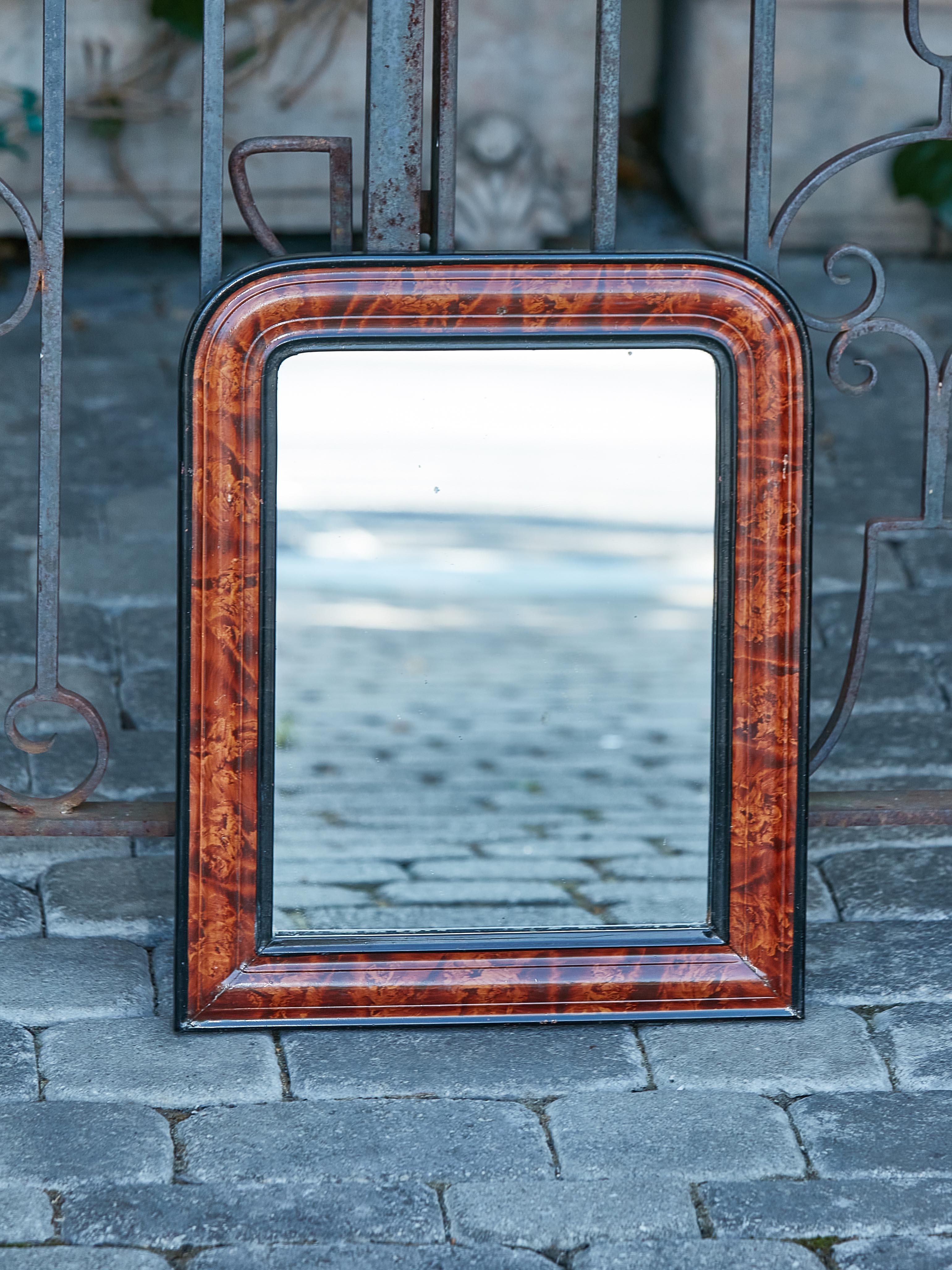 A small French Louis-Philippe style wooden mirror from the early 20th century, with tortoise style painted frame, brown and black accents. Elevate your interior with this exquisite small French Louis-Philippe style wooden mirror from the early 20th