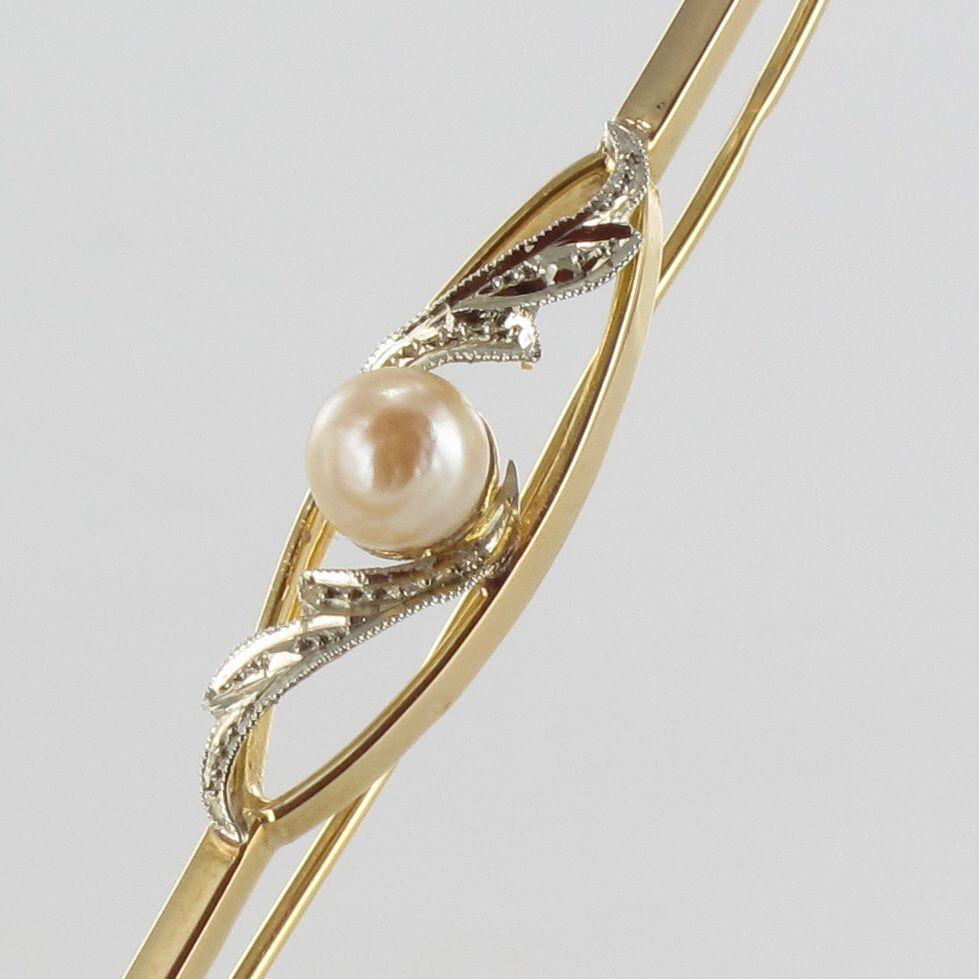Brooch in 18 karat yellow and white gold, eagle's head hallmark.
In the center of this bar brooch is set with a natural pink orient pearl shouldered on both sides with plant motifs chiseled in white gold. The whole is set on a frame with an openwork