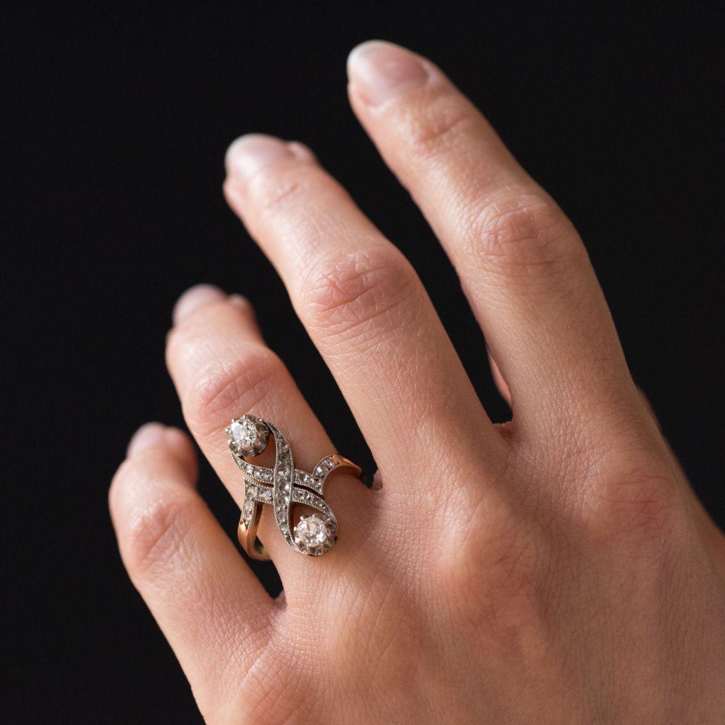 Ring in 18 karat yellow gold, eagle head hallmark and platinum.
This sublime antique ring boasts an elongated and delicate design. It is claw set with 2 cushion cut diamonds in an openwork décor with rose cut diamonds in beaded settings that