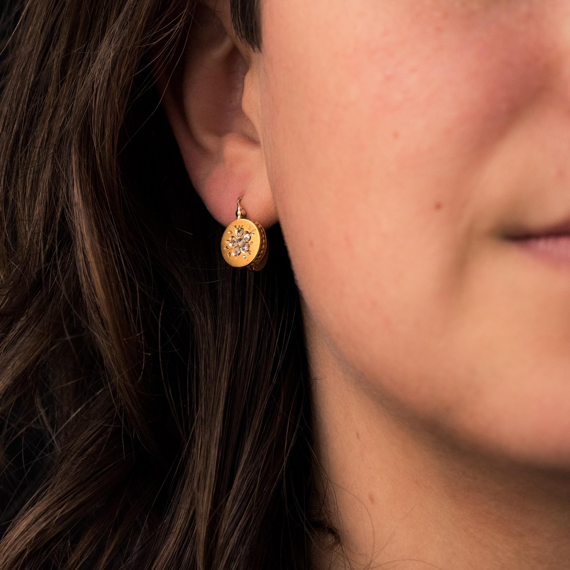 Earrings in 18 karat yellow gold, eagle's head hallmark.
Lovely antique drop earrings, each earring is made of a flat gold disc chiselled with a pansy flower, whose heart and petals are set with rose-cut diamonds. The clasp threads from the