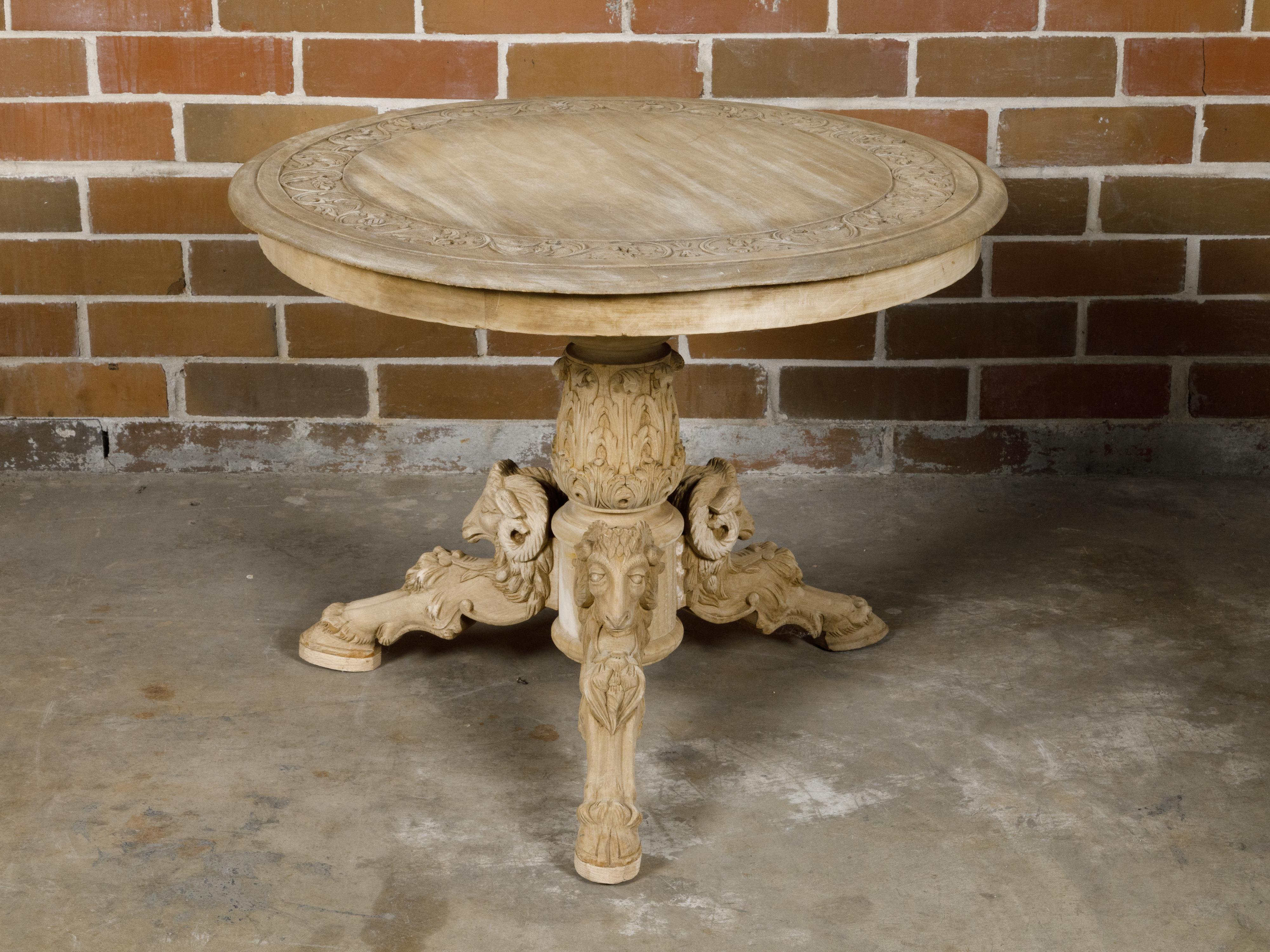 A French bleached wood pedestal table from circa 1900 with circular top and carved rams heads. Discover the timeless elegance of this French bleached wood pedestal table, circa 1900, a superb addition to any refined home decor. This exquisite table