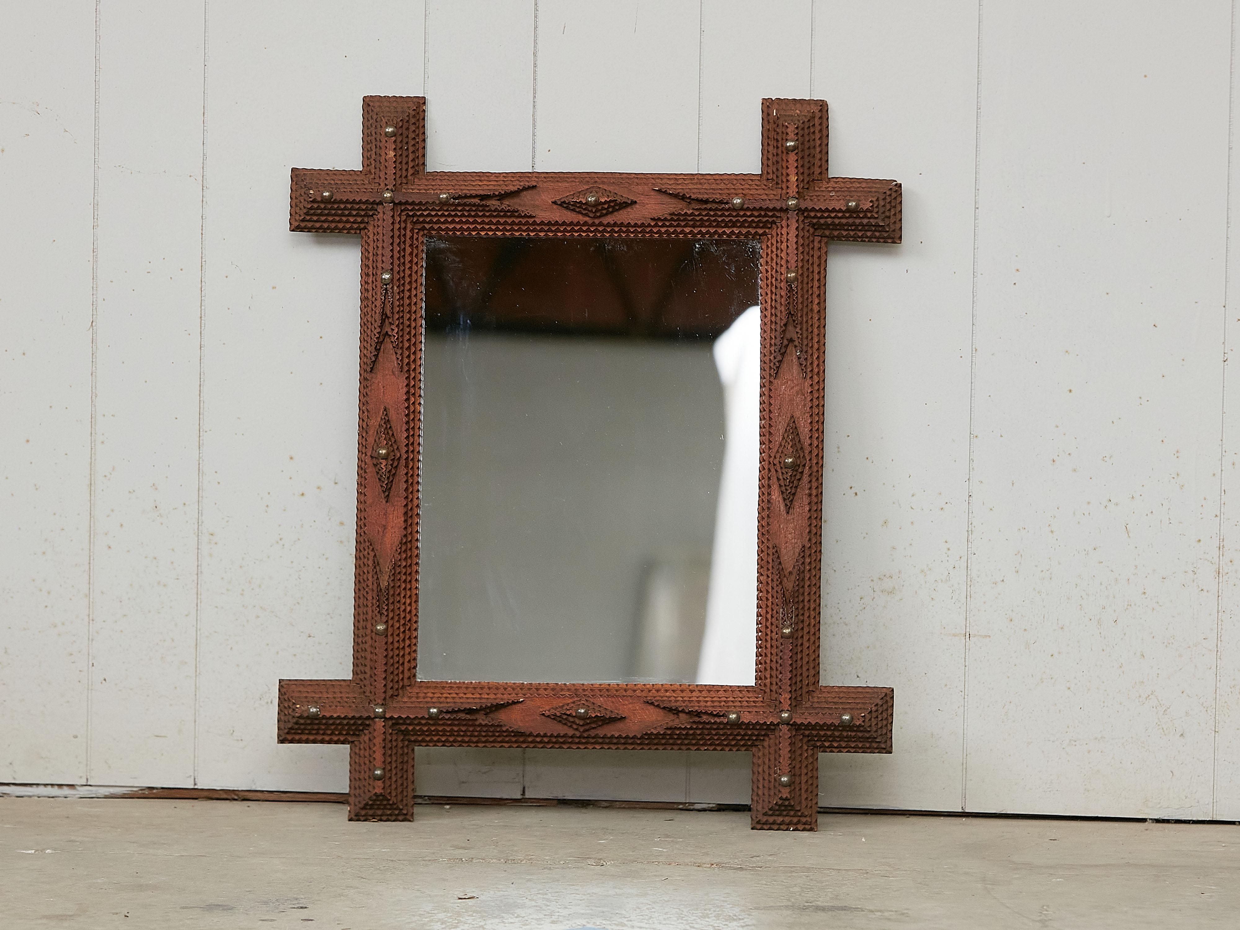 A French rectangular Tramp Art hand-carved wooden Folk mirror from the early 20th century, with raised diamond motifs, geometric patterns, intersecting corners and brass tacks. Created in France during the Turn of the Century which saw the