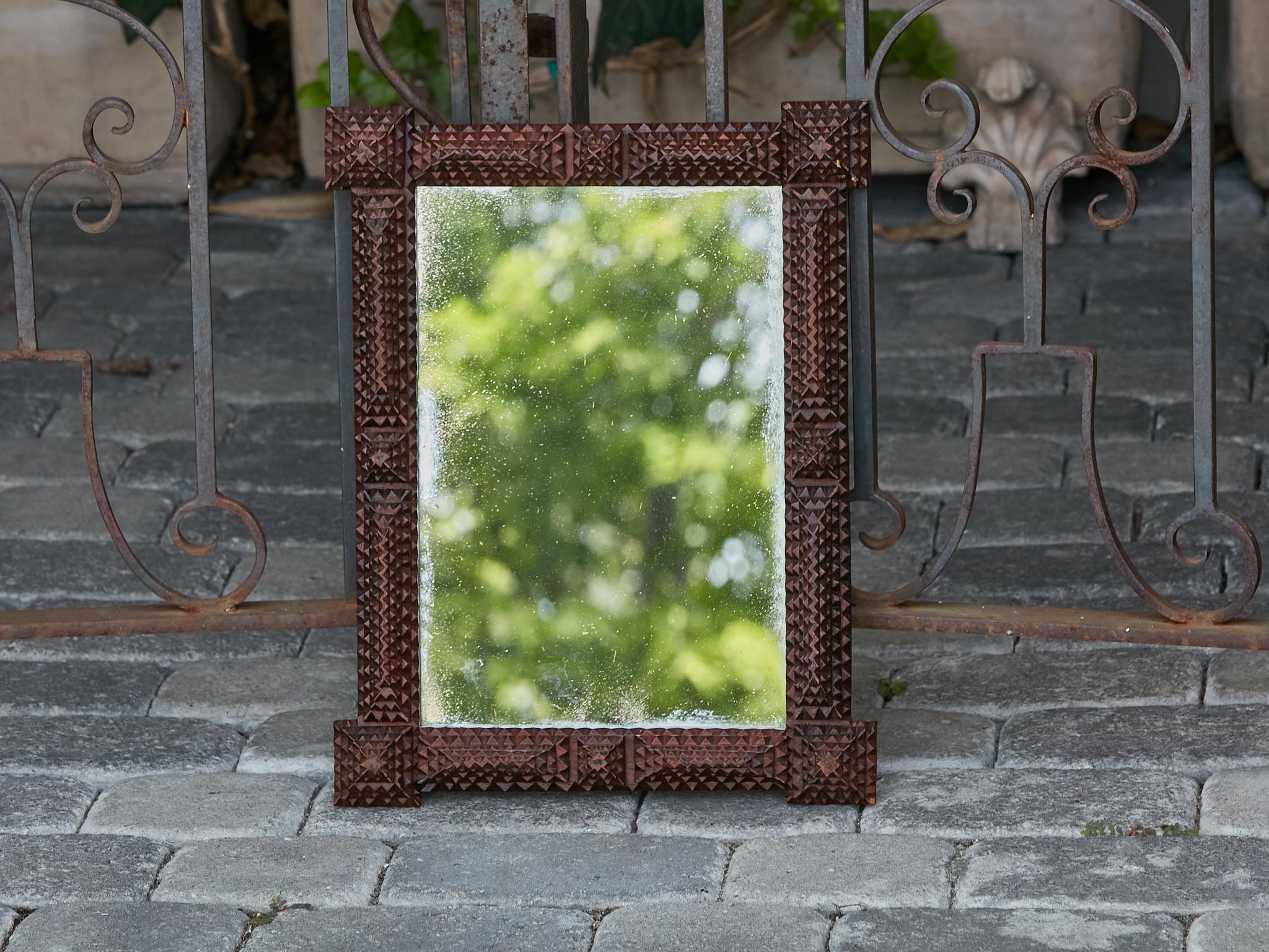 A French Tramp Art hand-carved wooden mirror from the Turn of the Century circa 1900, with pyramidal protruding corners and dark brown patina. Embrace the enduring beauty of folk art with this captivating French Tramp Art hand-carved wooden mirror
