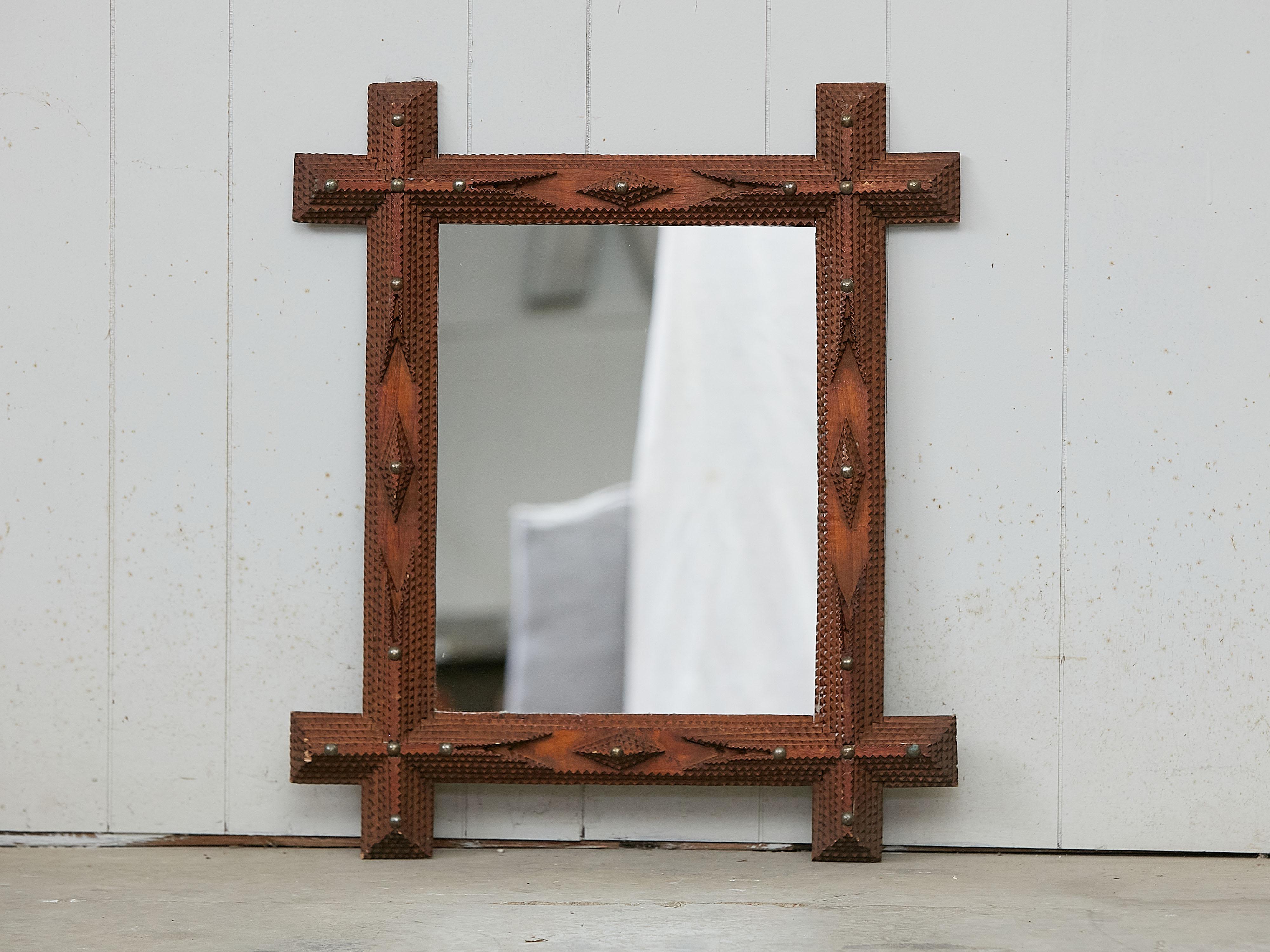 A French rectangular Tramp Art hand-carved wooden mirror from the early 20th century, with raised diamond motifs, geometric patterns and brass nailheads. Created in France during the early years of the 20th century, this wall mirror was hand carved