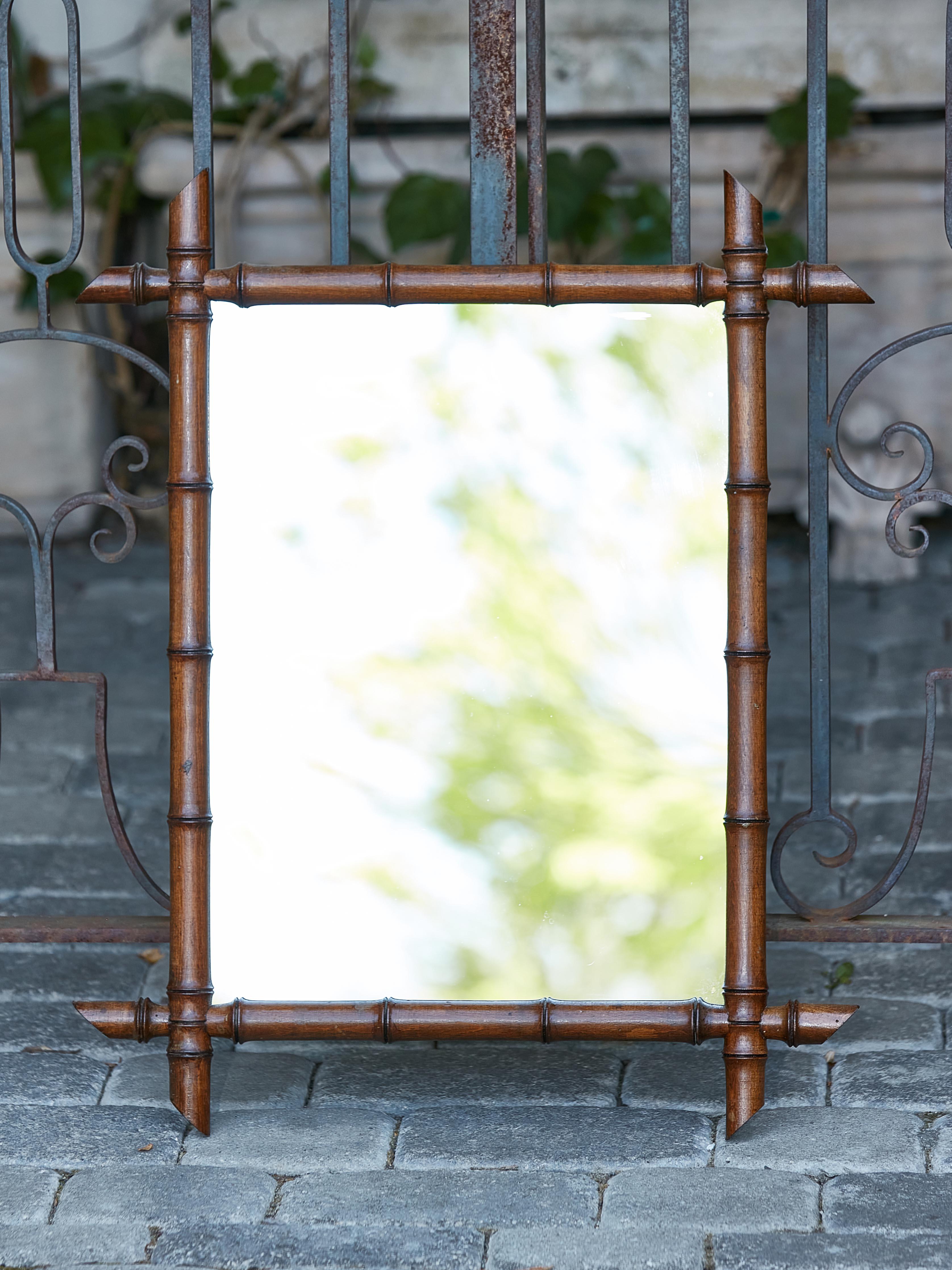 A French Turn of the Century faux-bamboo mirror from circa 1900 with intersecting corners, slanted accents and deep brown color. Imbue your living space with the rustic elegance of this French Turn of the Century faux-bamboo mirror, a period gem