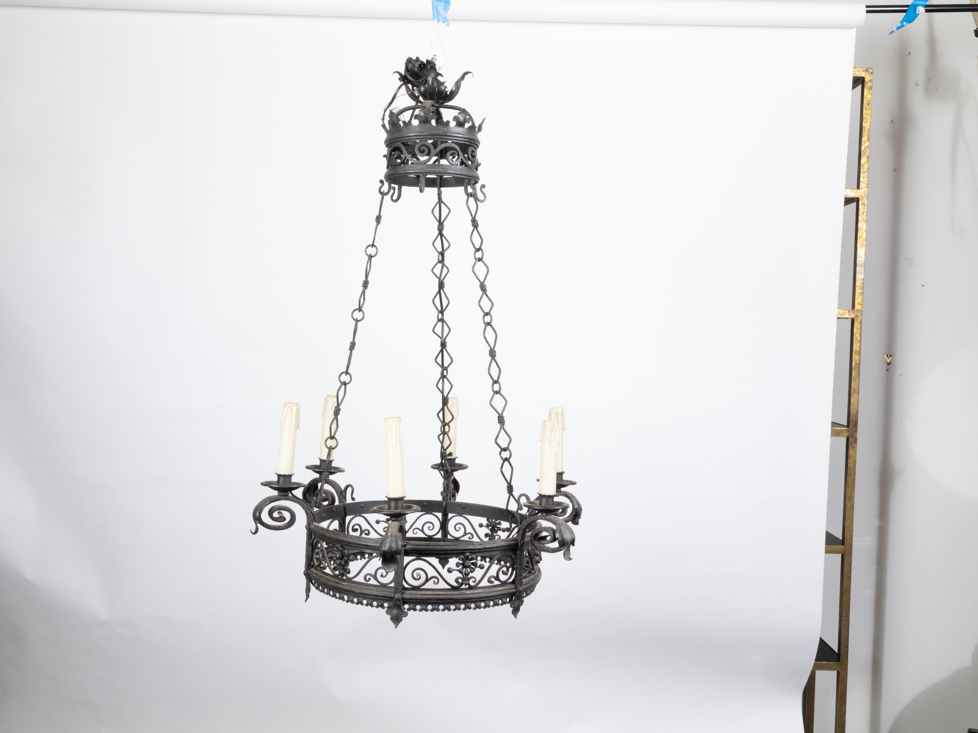 A French iron chandelier from the turn of the century, with six lights and scrollwork motifs. Created in France during the early years of the 20th century, this iron chandelier attracts the attention with its two rings of increasing size, each