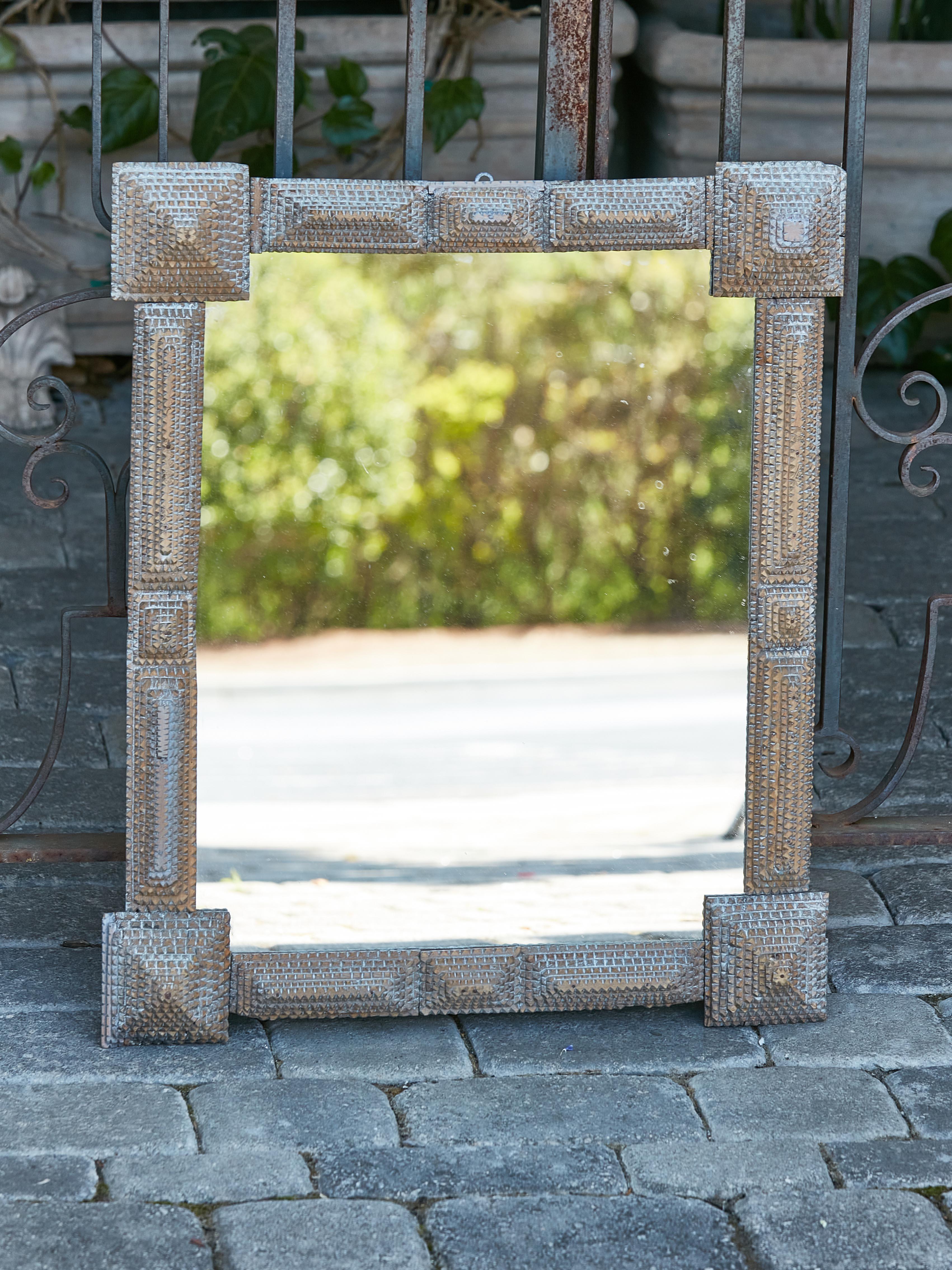 A French Tramp Art period hand-carved wooden mirror from circa 1900 with raised protruding corners, touches of light blue paint and pyramidal effects. Immerse yourself in the world of rustic allure and impeccable craftsmanship with this
