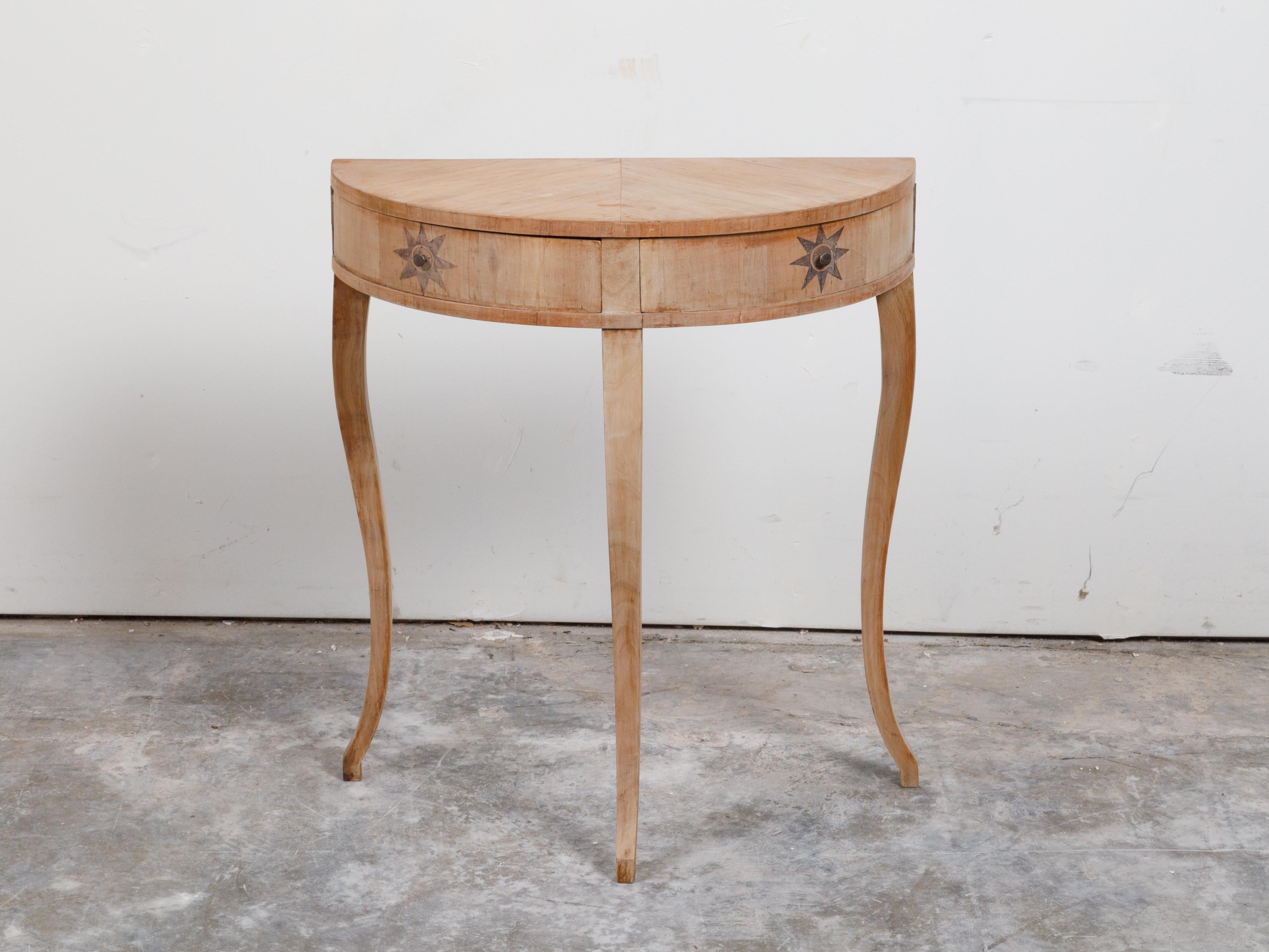 A French walnut veneered demi-lune console table from the early 20th century, with star inlay and swivel drawers. Created in France during the early years of the 20th century, this walnut demilune table features a semi-circular top sitting above two