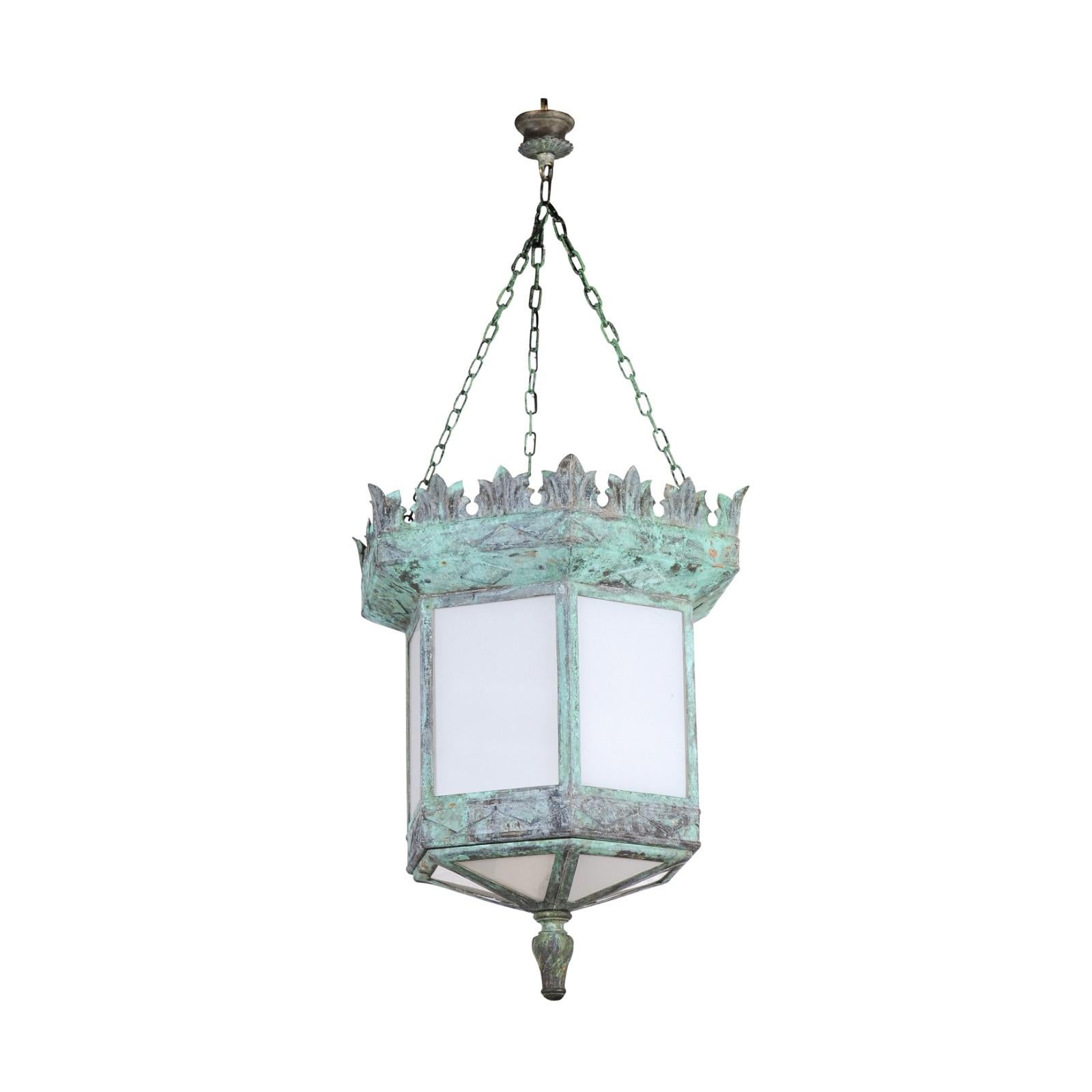 A French Art Deco hexagonal hanging lantern from the early 20th century with milk glass and verdigris patina. Created in France during the first quarter of the 20th century, this Art Deco lantern features an hexagonal body securing milk glass
