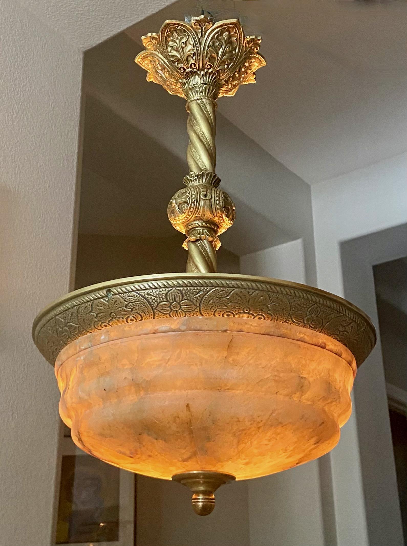 Early 2Oth century amber alabaster pendant light with brass fittings. The nicely carved amber shade alabaster has lots of natural veining...looks amazing when lit. The alabaster sits against a finely detailed outer rim, connecting to an elaborate