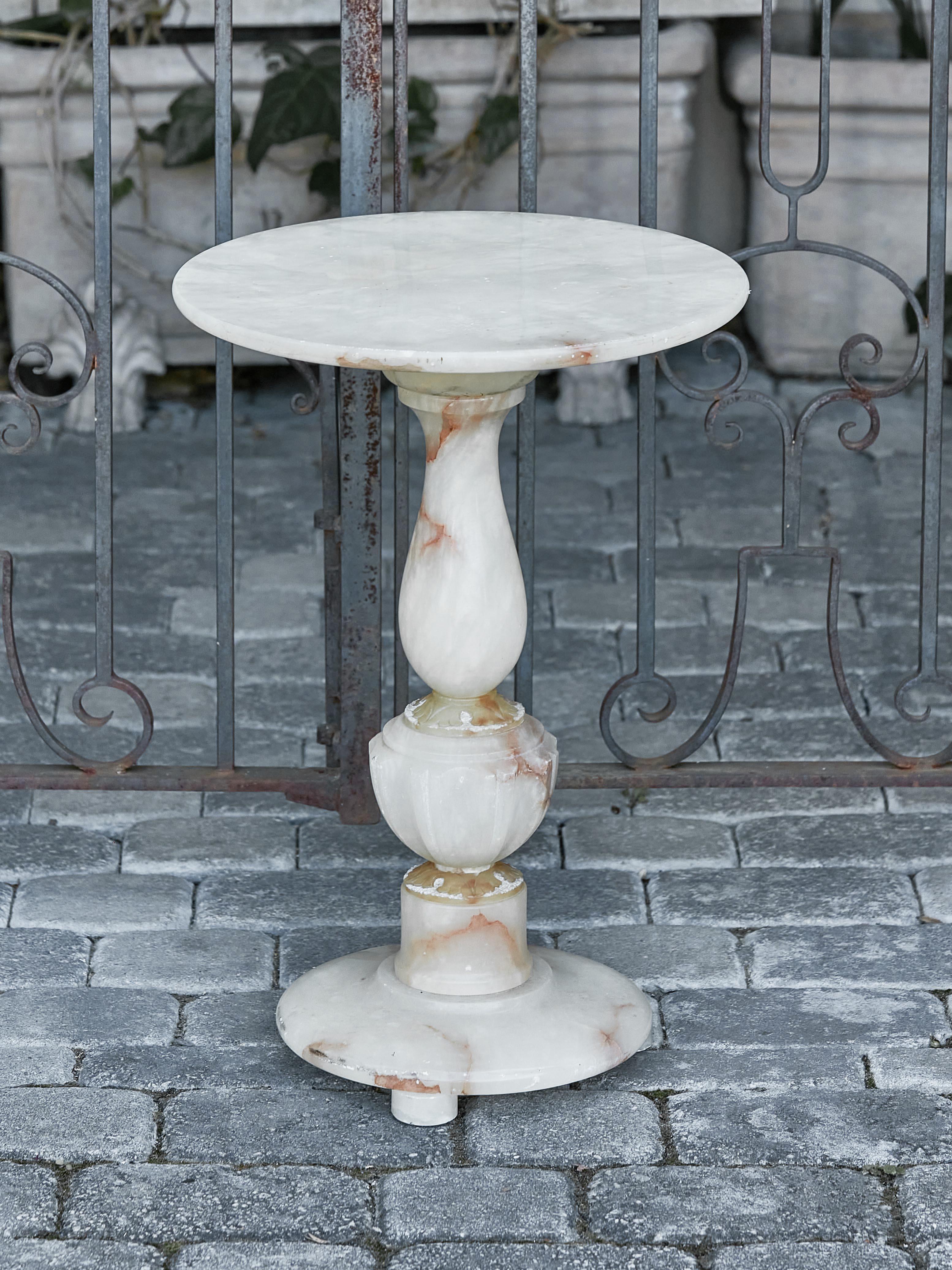 A French alabaster guéridon side table from circa 1920-1930 with circular top, pedestal base and petite feet. This French alabaster guéridon side table, dating from the 1920s to 1930s, exudes an air of timeless elegance and delicate beauty. Its