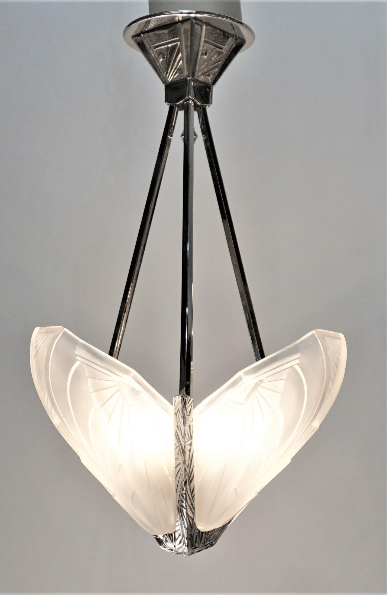 Stunning French Art Deco chandelier signed by E.J.G. having four clear frosted glass shade having intricate geometric motif. With polished nickel frame geometric deco details. Has been rewired for American use with eight candelabra sockets.
 