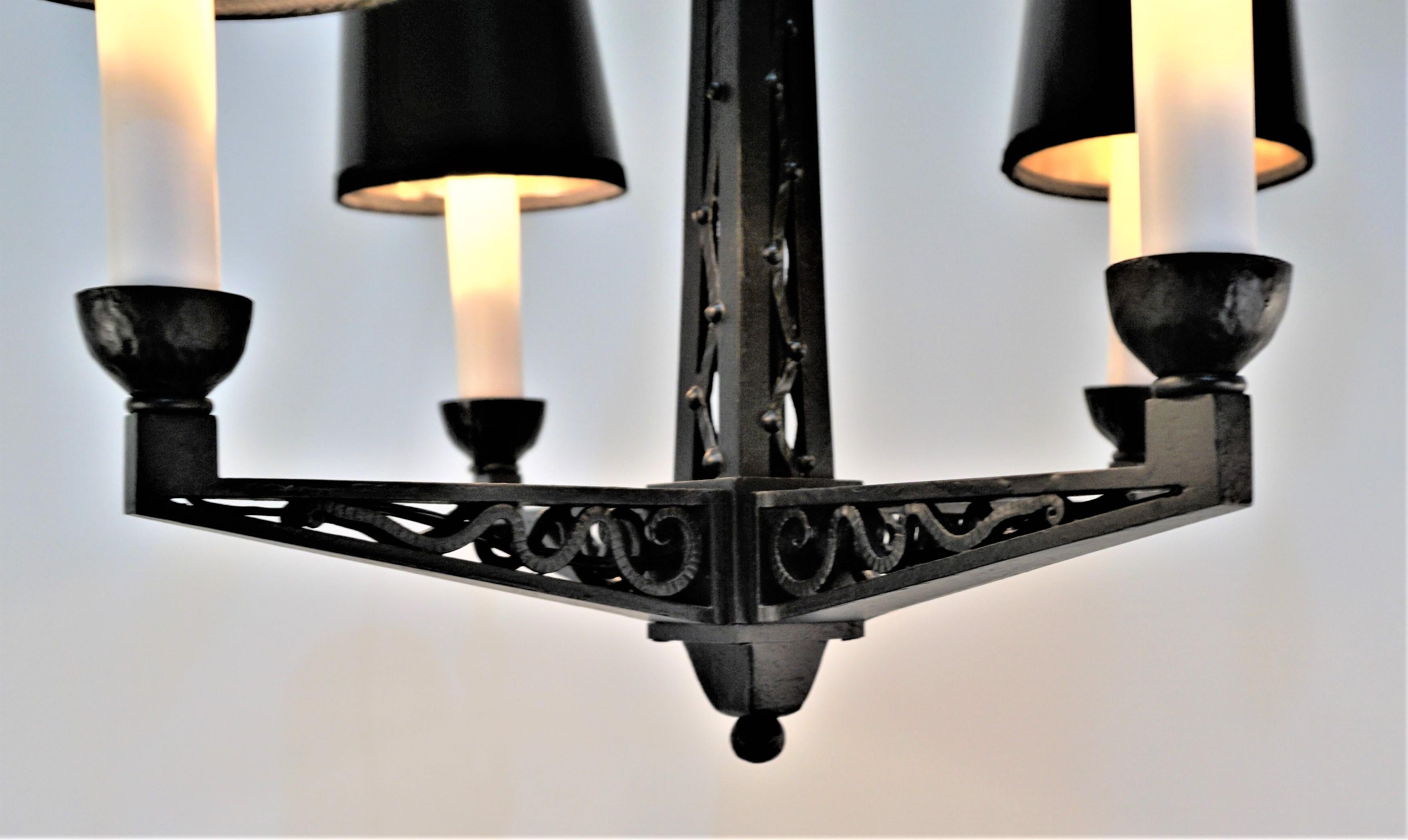 Magnifique lustre en fer laqué noir à quatre lumières datant des années 1920. 
La mesure de la largeur est le point le plus large sans les abat-jour.
La hauteur minimale est de 21