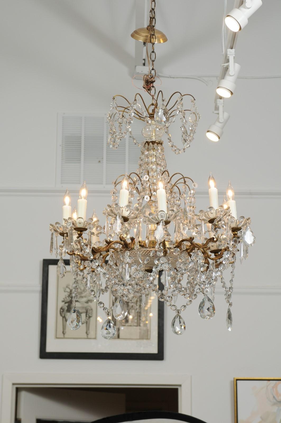 A French brass crystal twelve-light chandelier from the first half of the 20th century, with delicately scrolled arms and a multitude of faceted crystals. Magnificent brass and crystal chandelier from France, 1920s with 12 candles, all newly