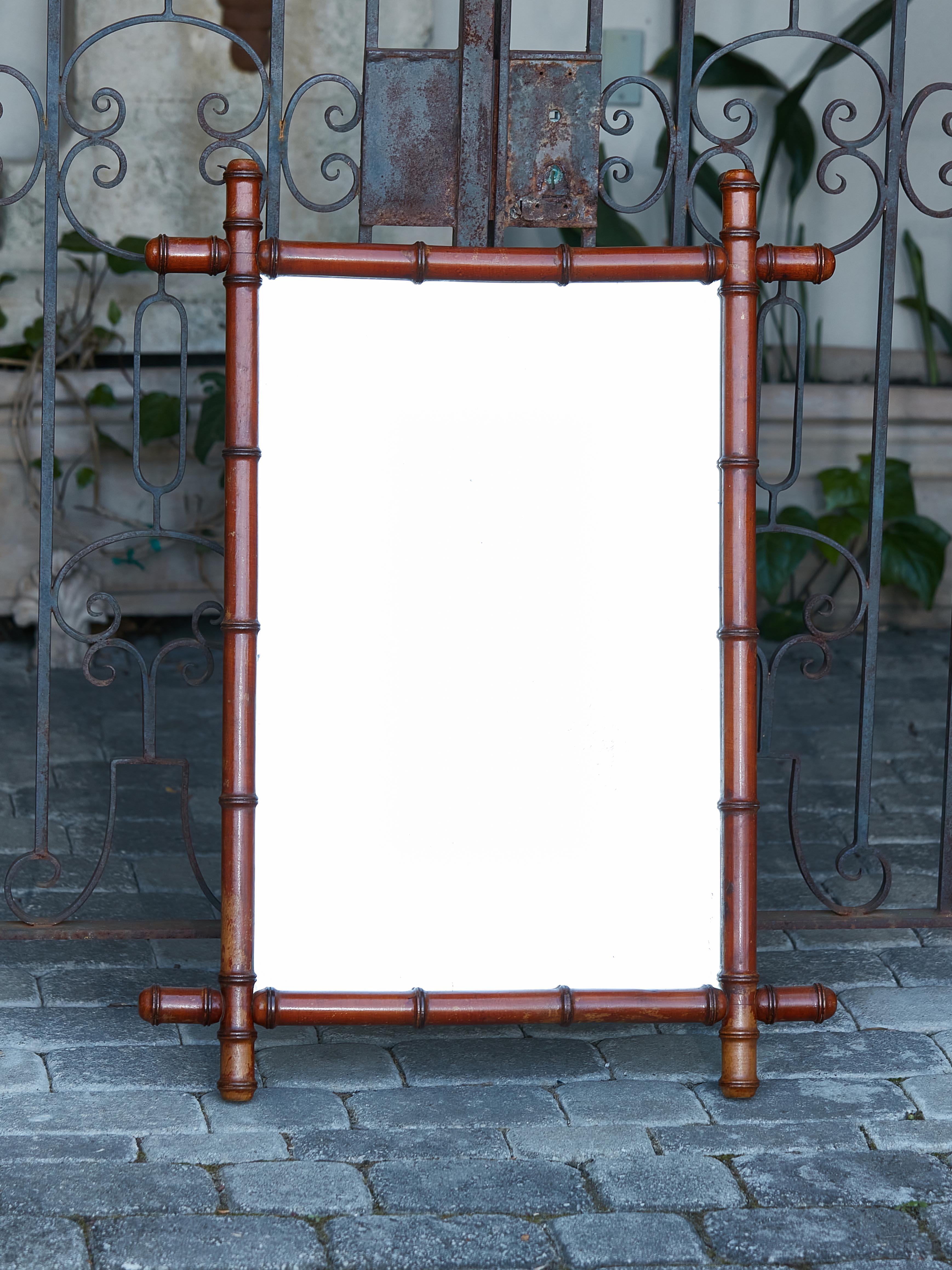 A French faux-bamboo mirror from circa 1920 made of walnut, with intersecting corners and rustic character. Immerse yourself in the nostalgic allure of the Roaring Twenties with this French faux-bamboo mirror, circa 1920. A perfect embodiment of