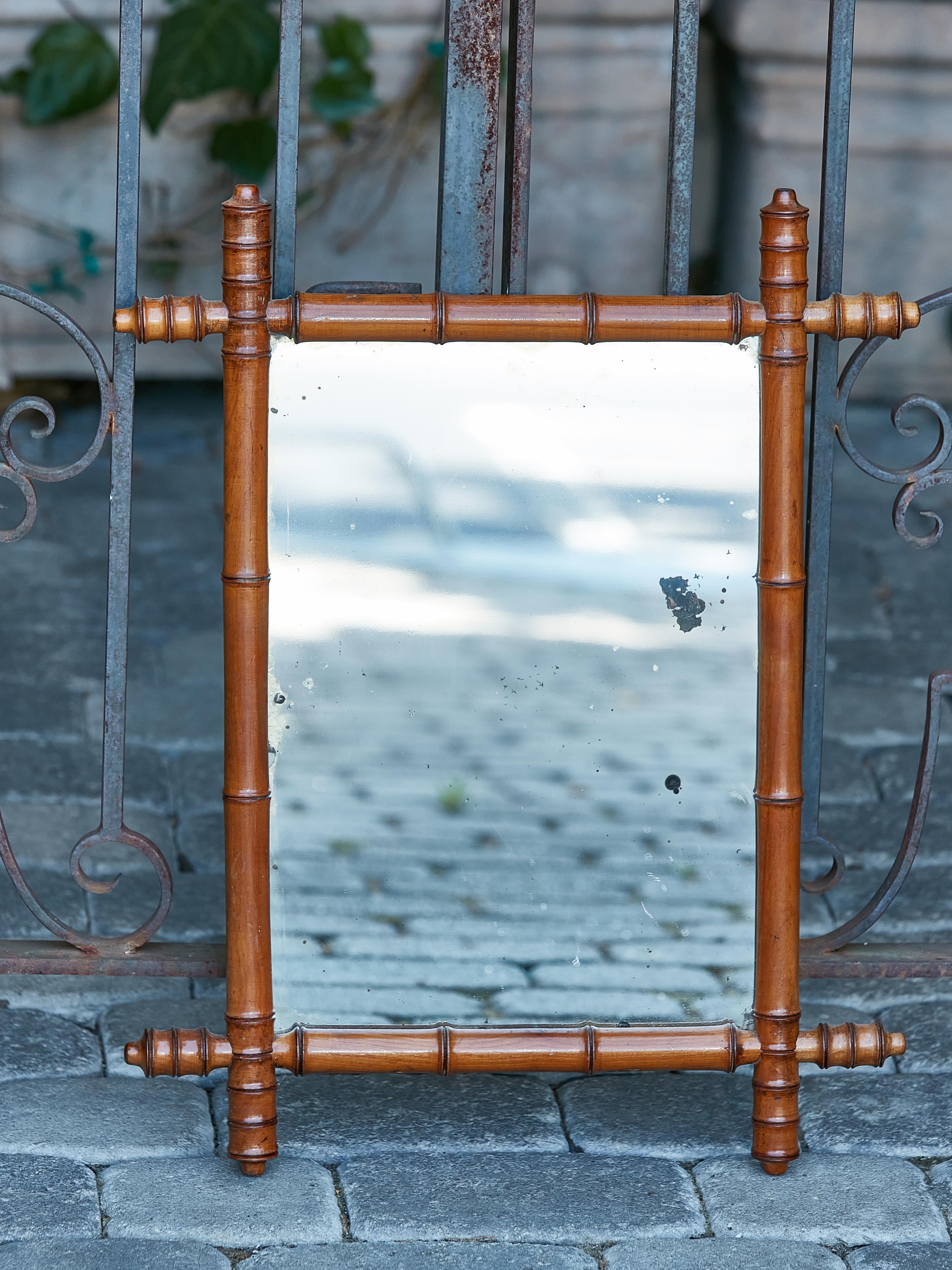 A French walnut faux-bamboo mirror from circa 1920 with reeded accents in the intersecting corners, brown color and rustic character. Introducing a rustic jewel, this French walnut faux-bamboo mirror, circa 1920, effuses an air of nostalgic
