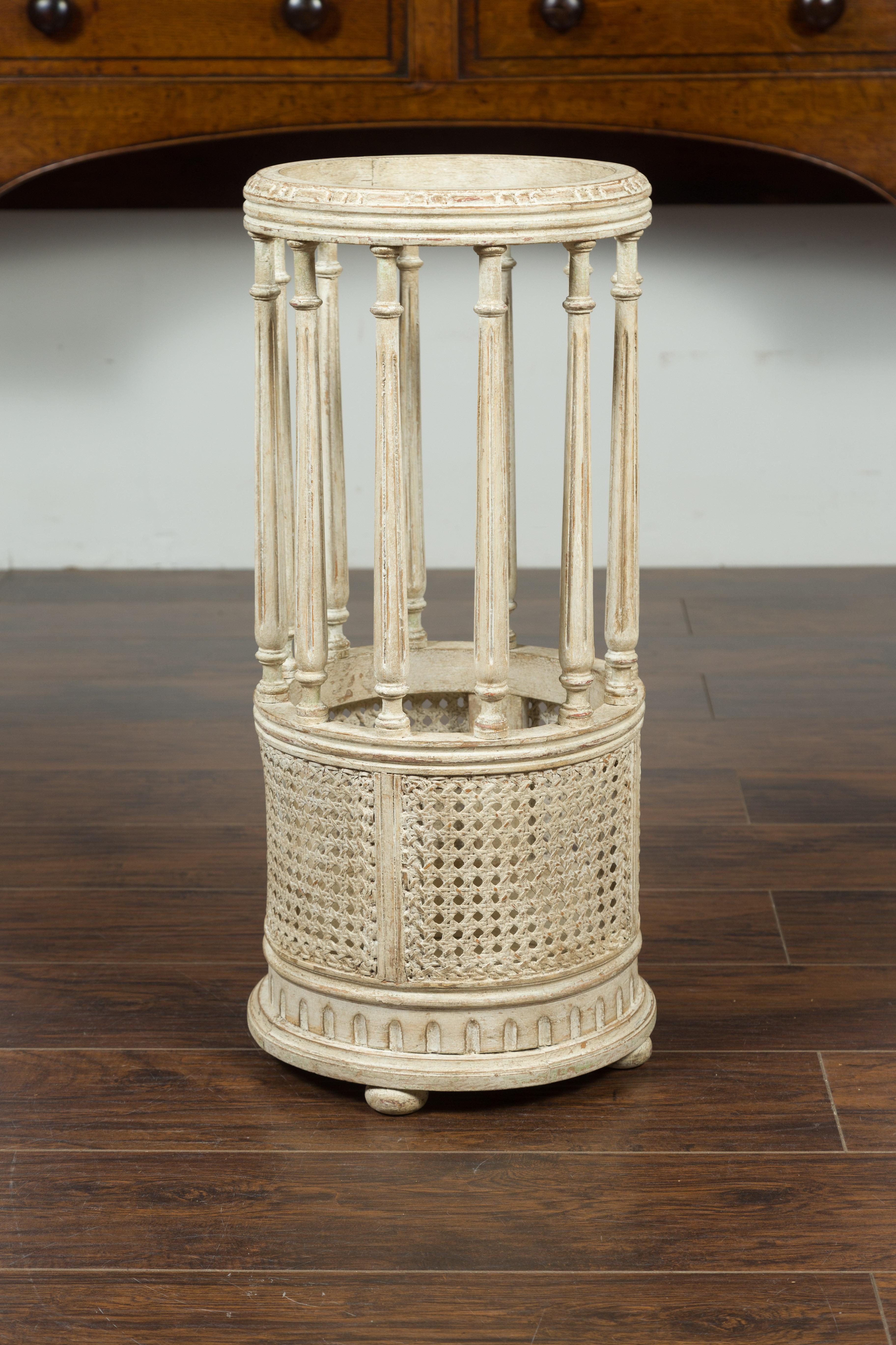 A French carved and painted wood and cane umbrella stand from the early 20th century, with fluted columns and bun feet. Created in France during the Années Folles (the Roaring Twenties), this painted umbrella stand features a circular top supported