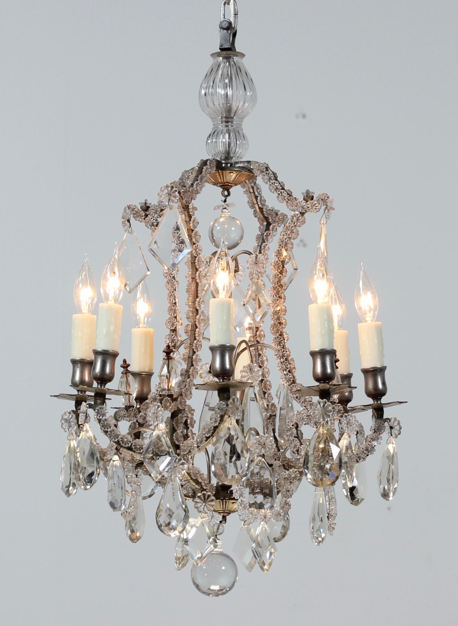 A fine and rare 1920s French crystal chandelier in the manner of Maison Bagues. The chandelier consists of a silver plated scrolled frame which has been delicately beaded with hundreds of crystal rosettes and decorated with faceted crystal prisms in