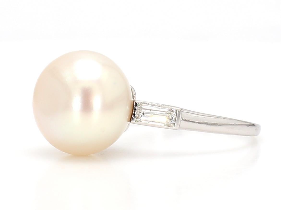 Introducing our exceptional Natural Pearl Art Deco Ring, a rare beauty that marries the allure of diamonds with the timeless elegance of platinum in a stunning French 1920s design. This exquisite ring boasts a 9mm center diamond of cream color,