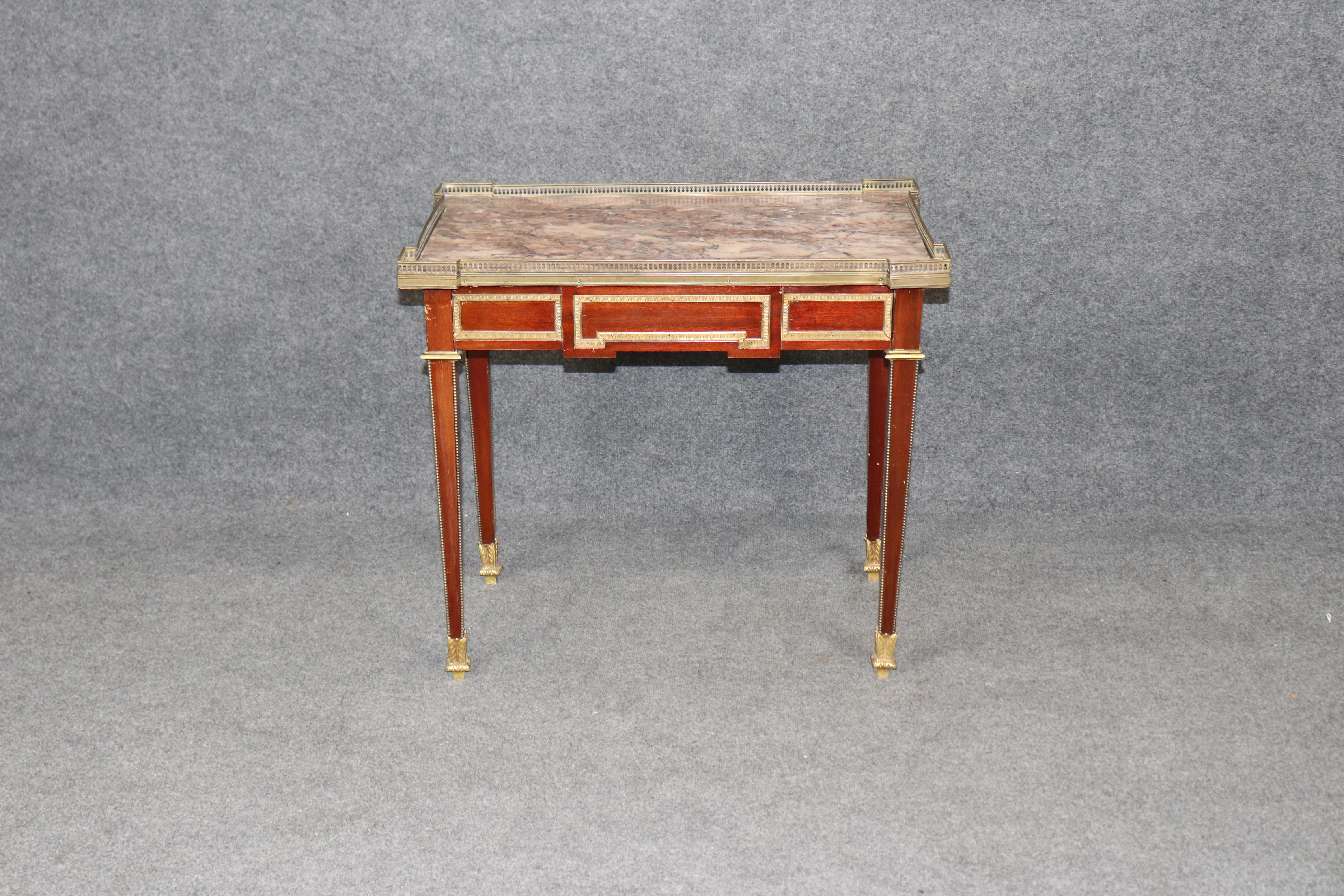 Eleva tu interior con esta exquisita mesa central francesa de 1920 montada en bronce, un refinado ejemplo del diseño neoclásico de principios del siglo XX. Elaborada con elegancia y precisión, esta mesa antigua presenta un tablero de mármol Breccia