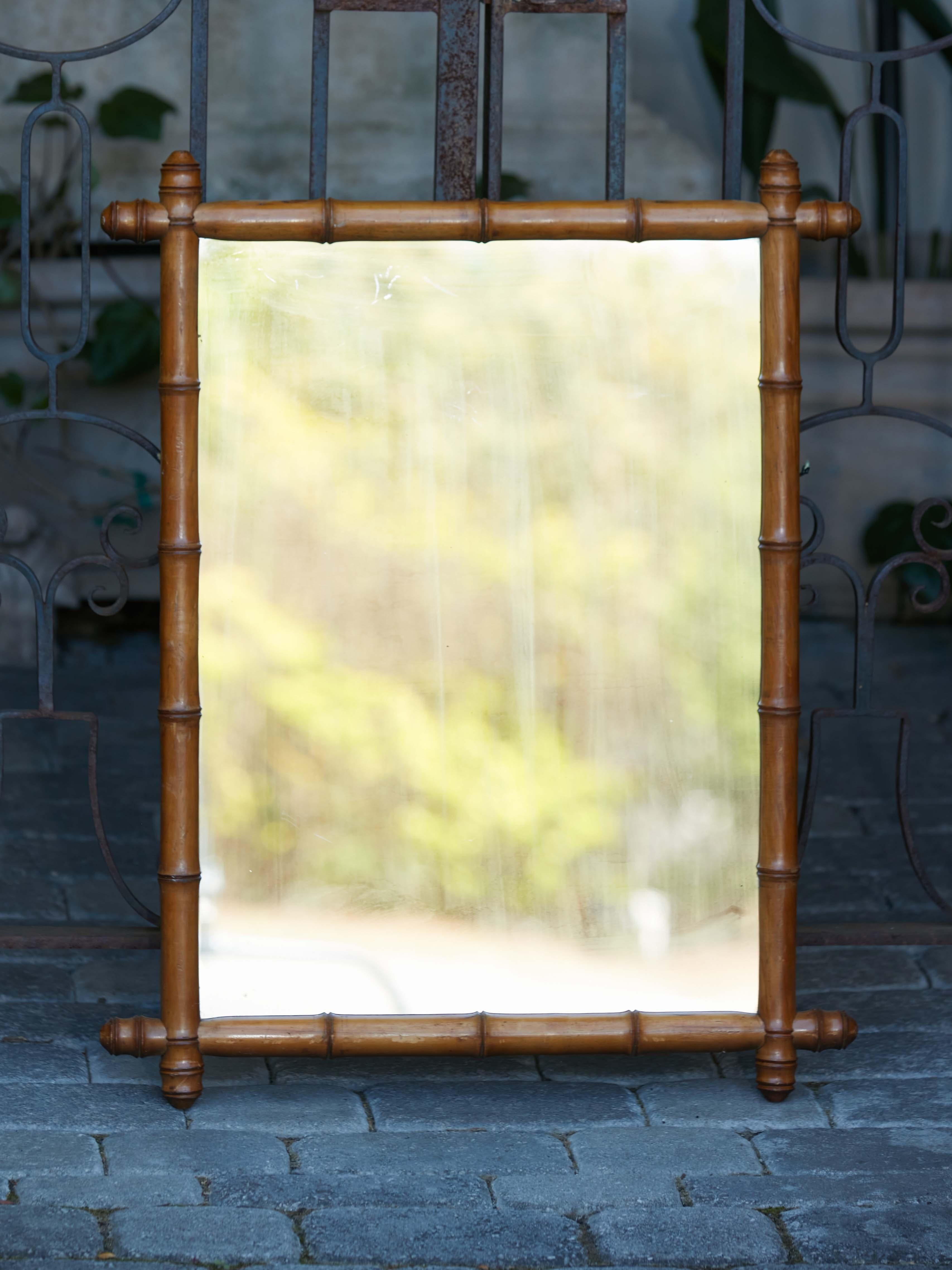 A rustic French faux-bamboo wooden mirror from the early 20th century, with brown patina and turned protruding corners. Transport yourself to the charm of the Roaring Twenties with this rustic French faux-bamboo wooden mirror from the early 20th