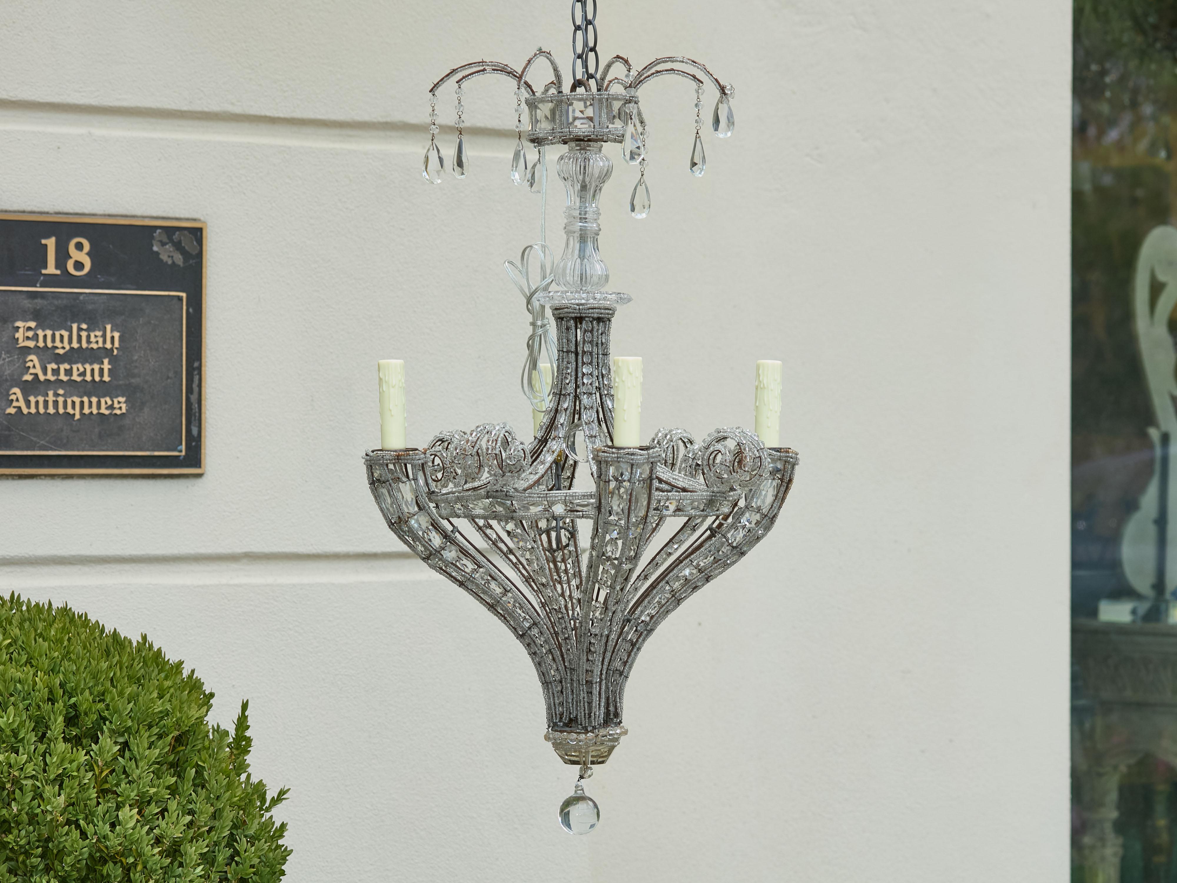 Lampadario francese a quattro luci del 1920 circa con bracci ricurvi, cristalli sfaccettati e fili di perline. Questo squisito lampadario francese a quattro luci del 1920 circa affascina con il suo design elegante e gli abbellimenti scintillanti. Il
