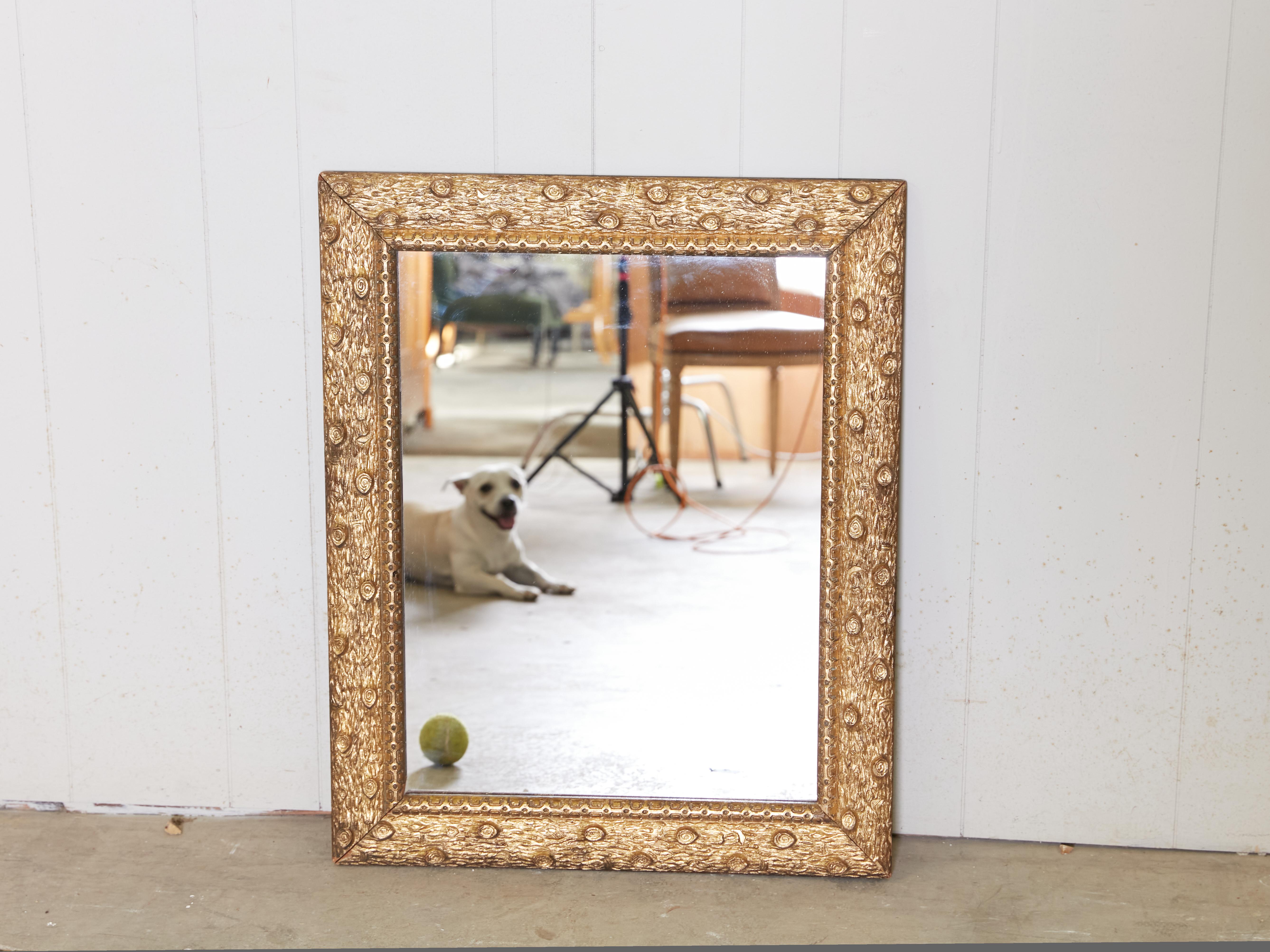 A French giltwood mirror from the early 20th century, with faux-bois carved frame and clear mirror plate. Created in France during the first quarter of the 20th century in the period called the Années Folles (the Roaring Twenties), this rectangular
