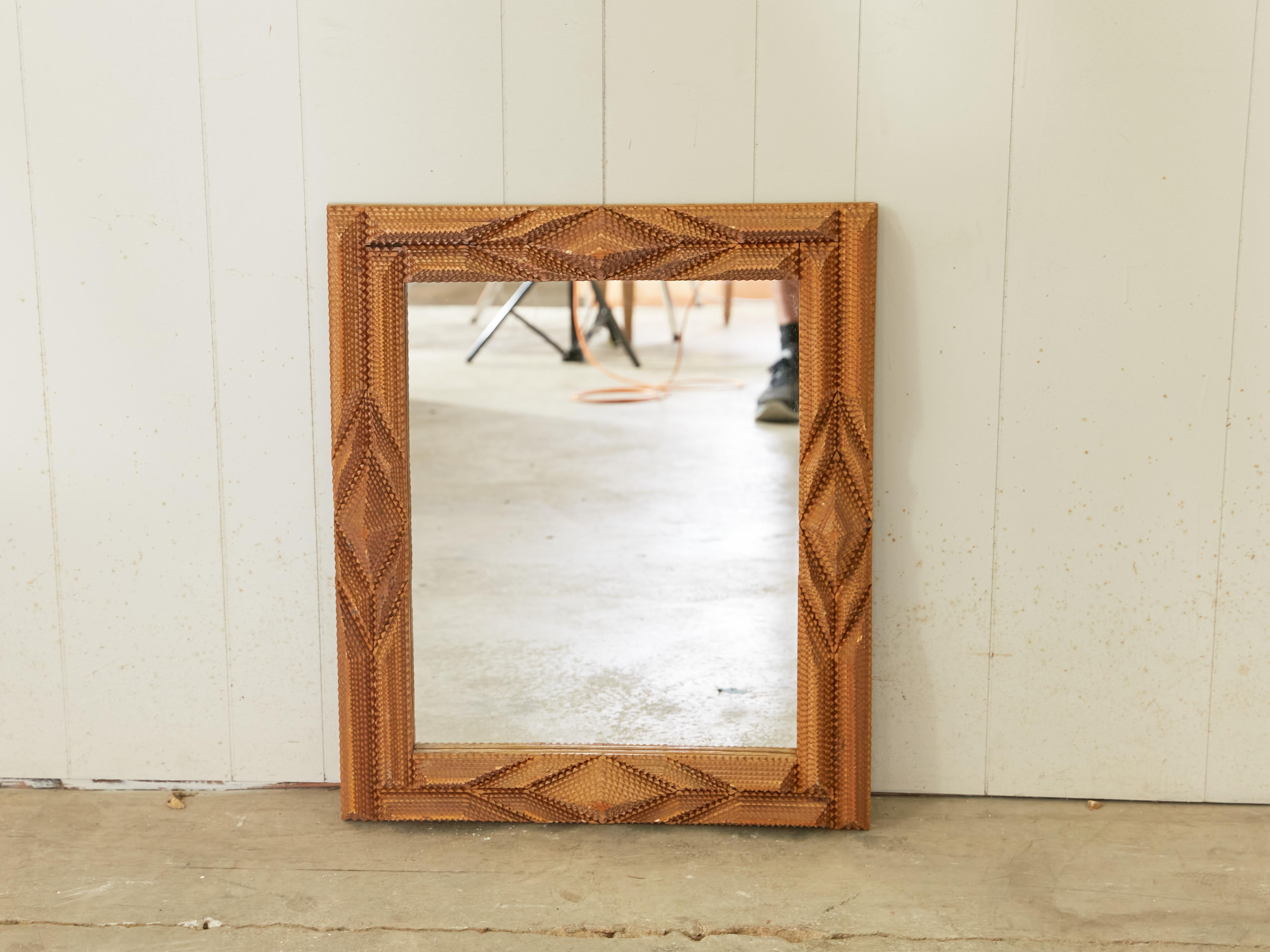 A French rectangular Tramp Art hand-carved wooden mirror from the early 20th century, with raised diamond motifs and geometric patterns. Created in France during the first quarter of the 20th century, this wall mirror was hand carved in the manner