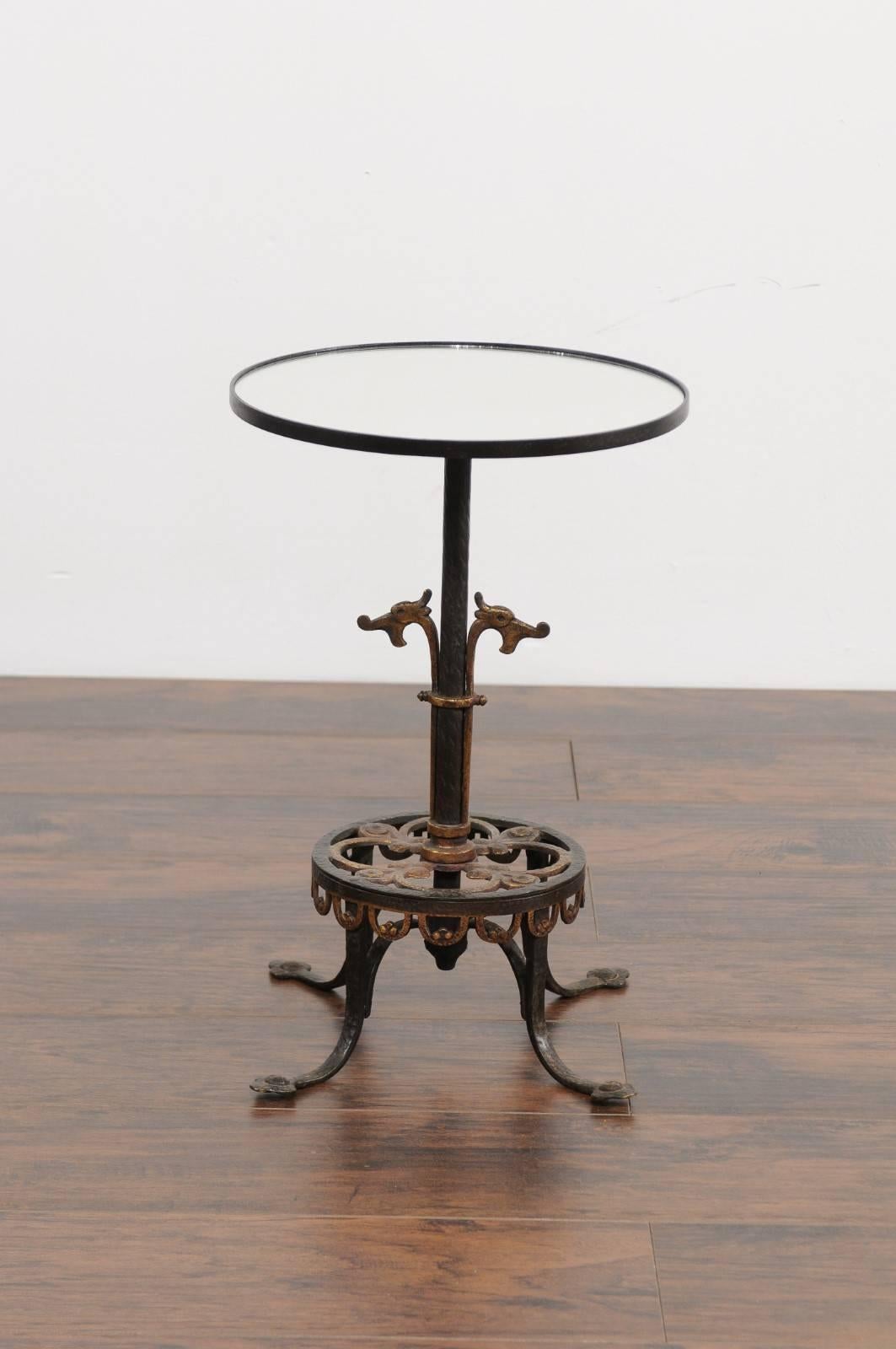 A French iron drink table from the early 20th century with stylized dragon motifs and new mirrored top. Born during the dynamic Années Folles (Roaring Twenties), this French drink table features a circular top supporting a custom-made new mirror,