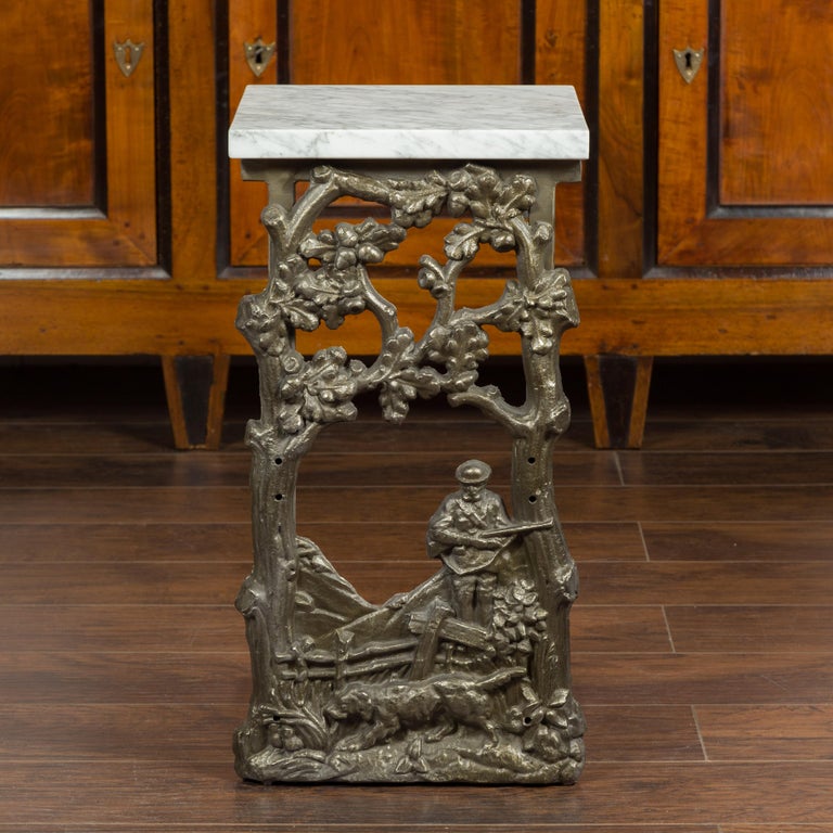A French iron fragment from the early 20th century, made into a drinks table with white veined marble top. We have two tables available, priced and sold each $3,750. Created in France during the 1920s, this iron fragment depicts a hunter carrying a