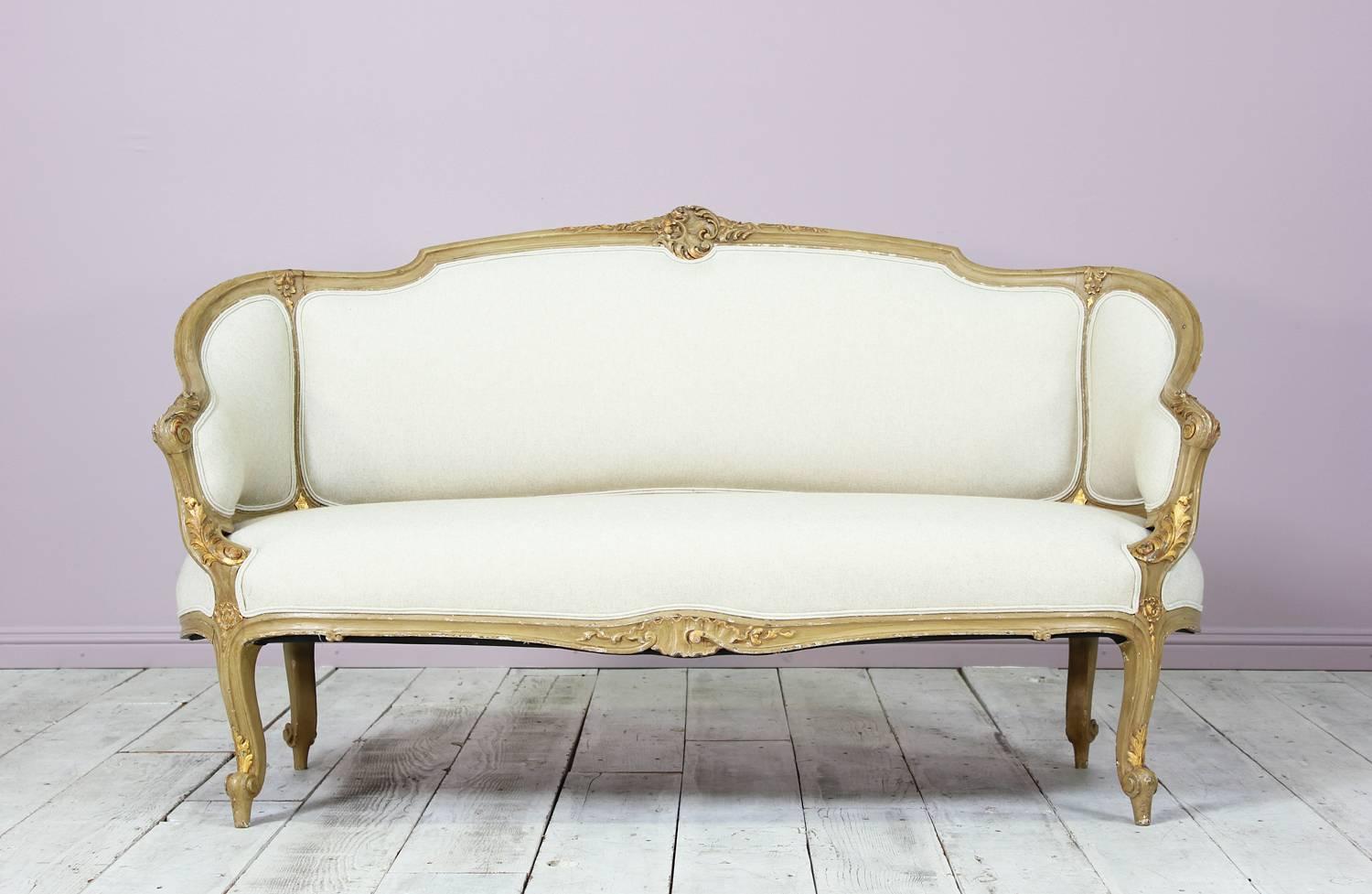 French, 1920s painted and parcel-gilt carved wood Louis XV style settee with new linen canvas upholstery. Paint finish is naturally distressed. The settee is sturdy and newly upholstered in a beautiful and durable linen-canvas fabric. Ready for many