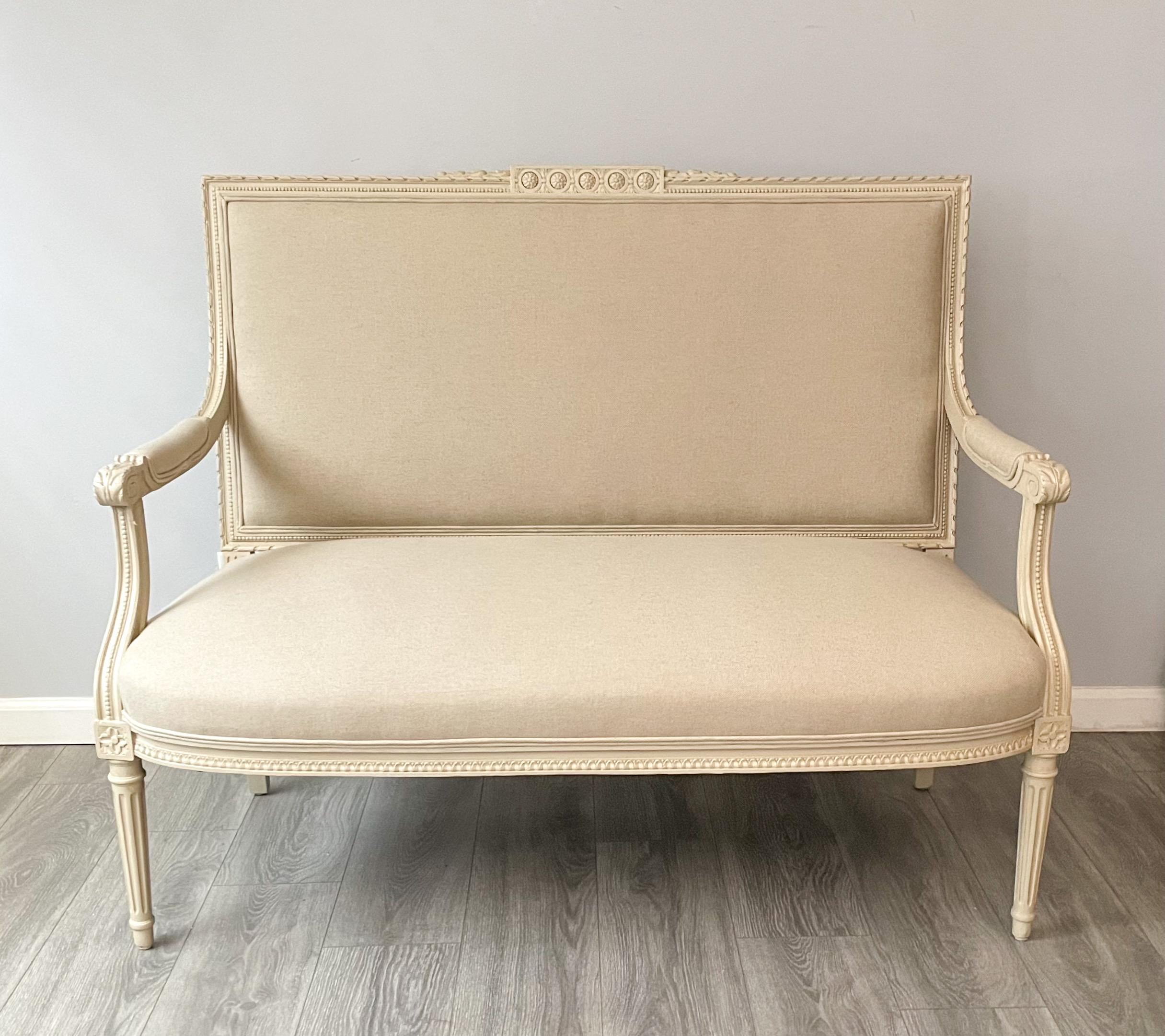 Beautiful, French 1920s settee in the Louis XVI style.

The settee features an intricate but tastefully carved wood frame that’s been newly painted in a crème color with a light, hand-rubbed antique glaze finish. 

New Belgian linen