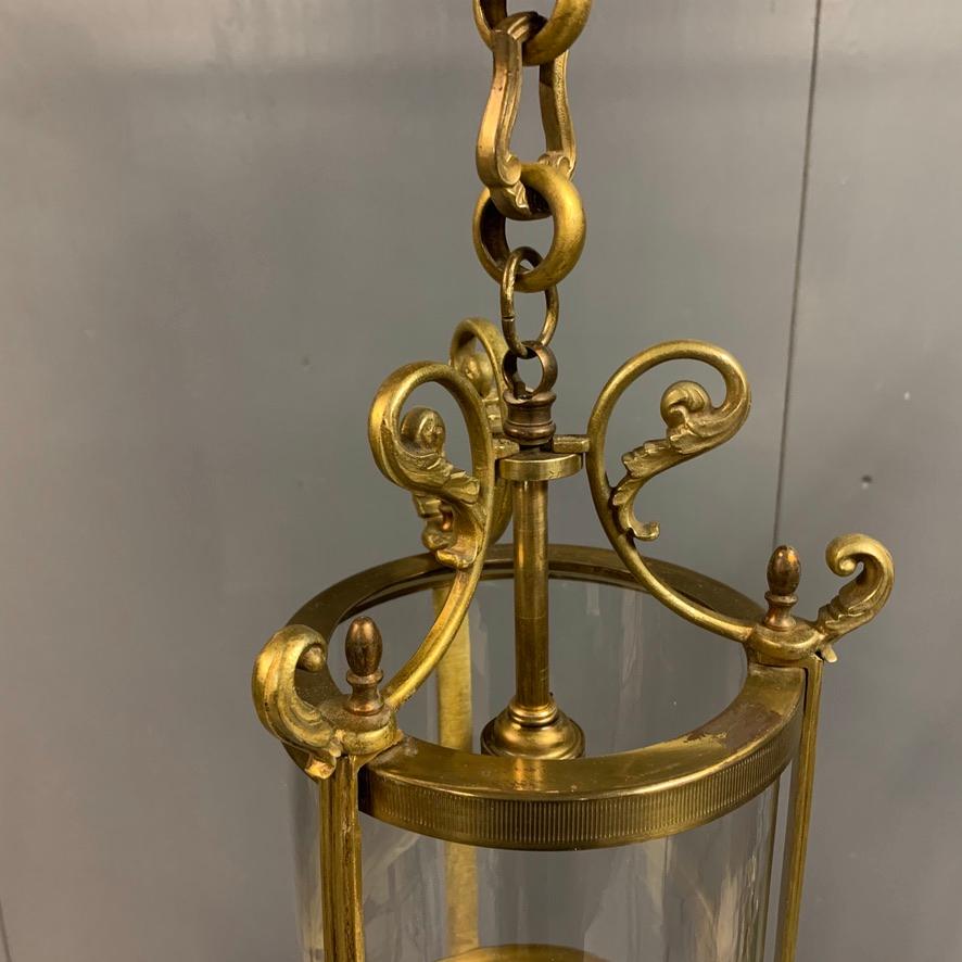 Lovely pair of French brass cylinder lanterns with scrolls to the lanterns and with their original brass hanging chain and ceiling roses.
Good original cylinder glass to both lanterns and both in really good condition. 
They are a neat proportion,