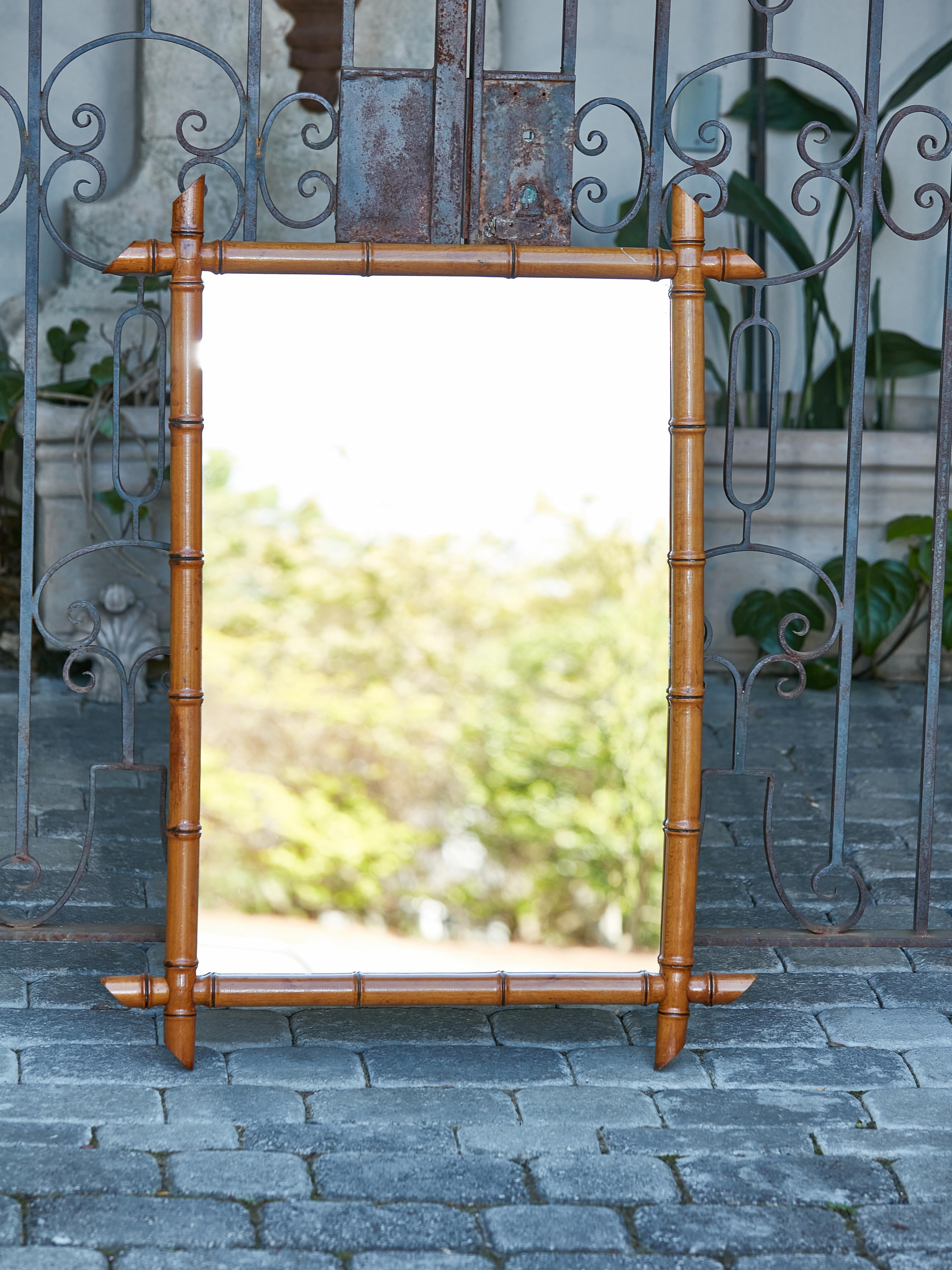 A French rectangular faux-bamboo walnut mirror from the early 20th century, with brown patina. Immerse yourself in the rustic charm of this early 20th-century French faux-bamboo walnut mirror. Designed in the rich tapestry of French craftsmanship,