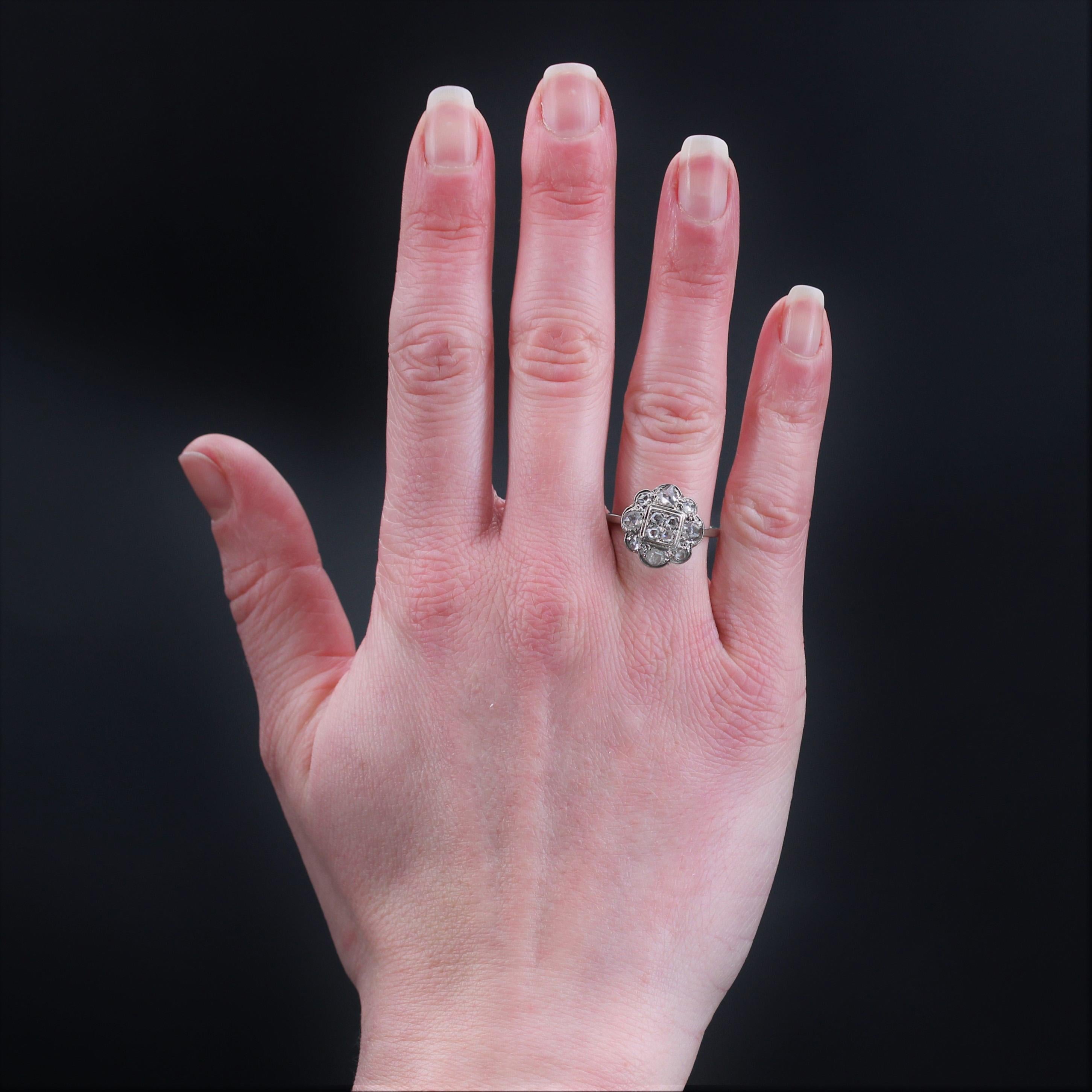 Ring aus 18 Karat Weißgold, Eulenpunze.
Eleganter antiker Ring, dessen Fassung eine stilisierte Blume darstellt, deren Blütenblätter abwechselnd mit Diamanten im Rosenschliff in verschiedenen Größen besetzt sind, und in der Mitte ein quadratisches