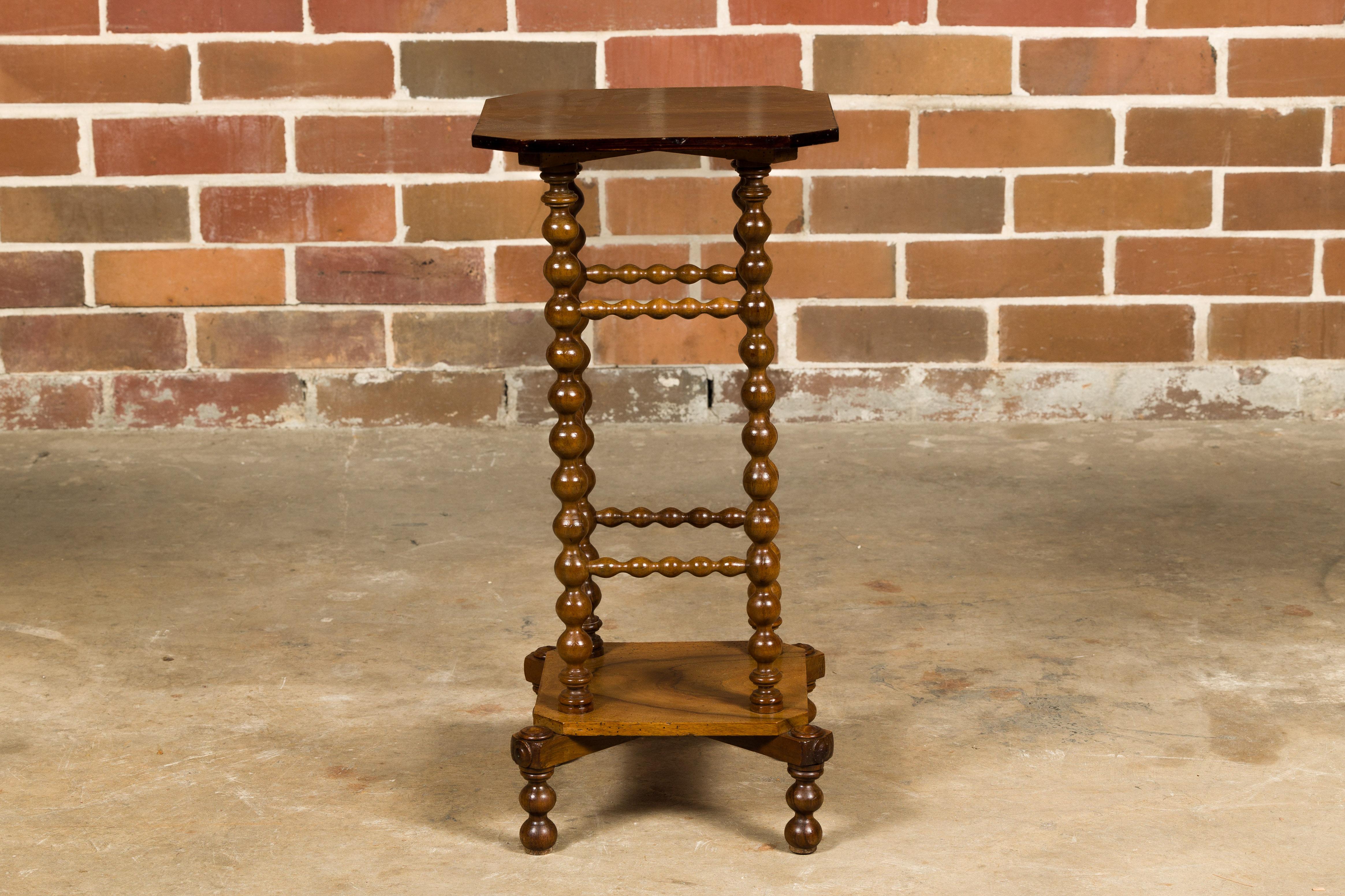A French walnut bobbin legs guéridon side table from circa 1920-1930, with lower shelf. This delightful French walnut guéridon side table, dating from the 1920s to 1930s, effortlessly blends elegance and functionality. Its petite size and charming