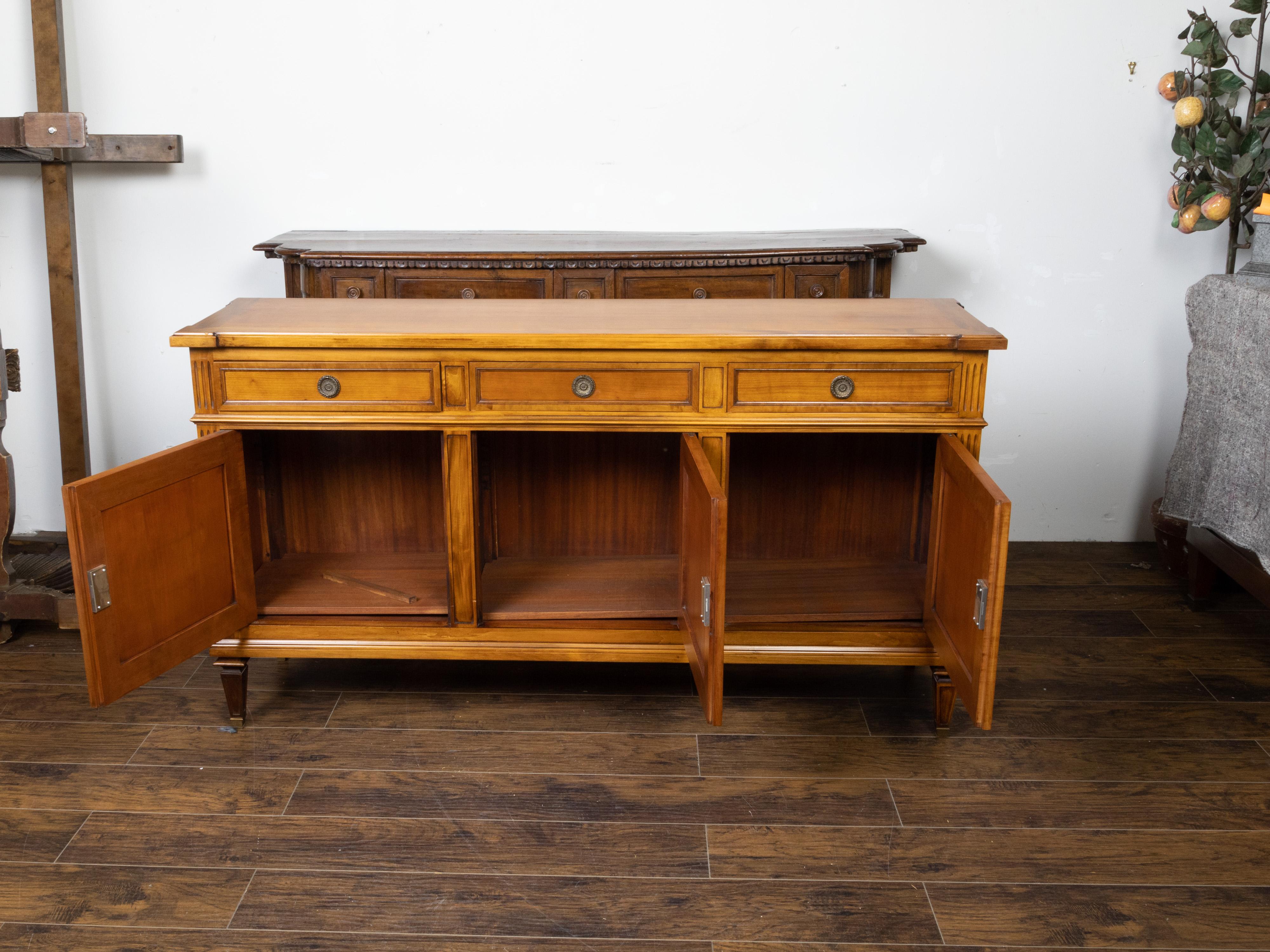 A French walnut enfilade from the early 20th century, with three drawers over three doors. Created in France during the first quarter of the 20th century, this walnut enfilade features a rectangular top with protruding corners, sitting above three