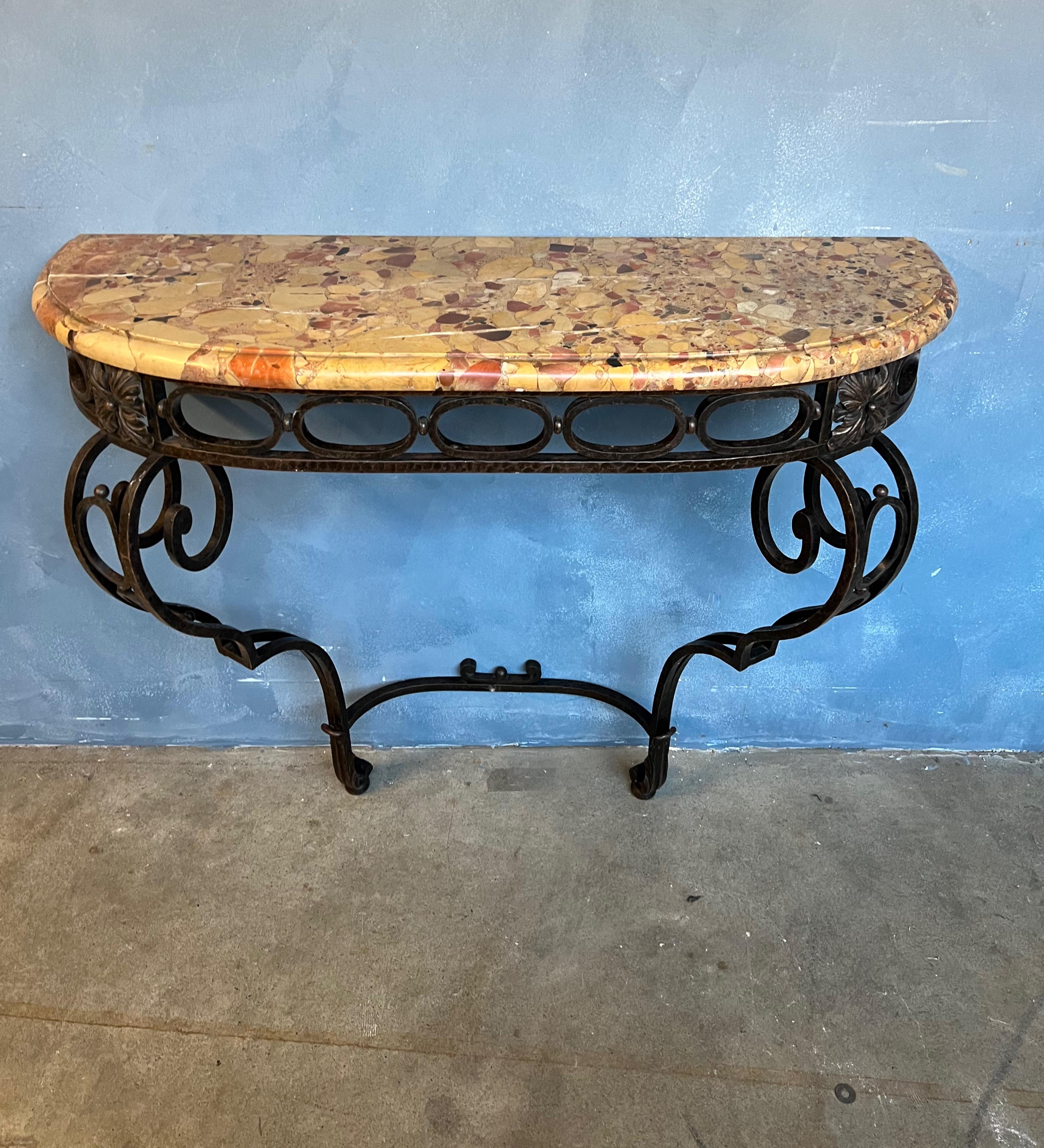 This beautiful and unique iron console with a marble top dating back to the 1920s has a stunningly intricate wrought iron base that is composed of delicate scroll and foliage patterns, a classic French motif. The dark patina is original,