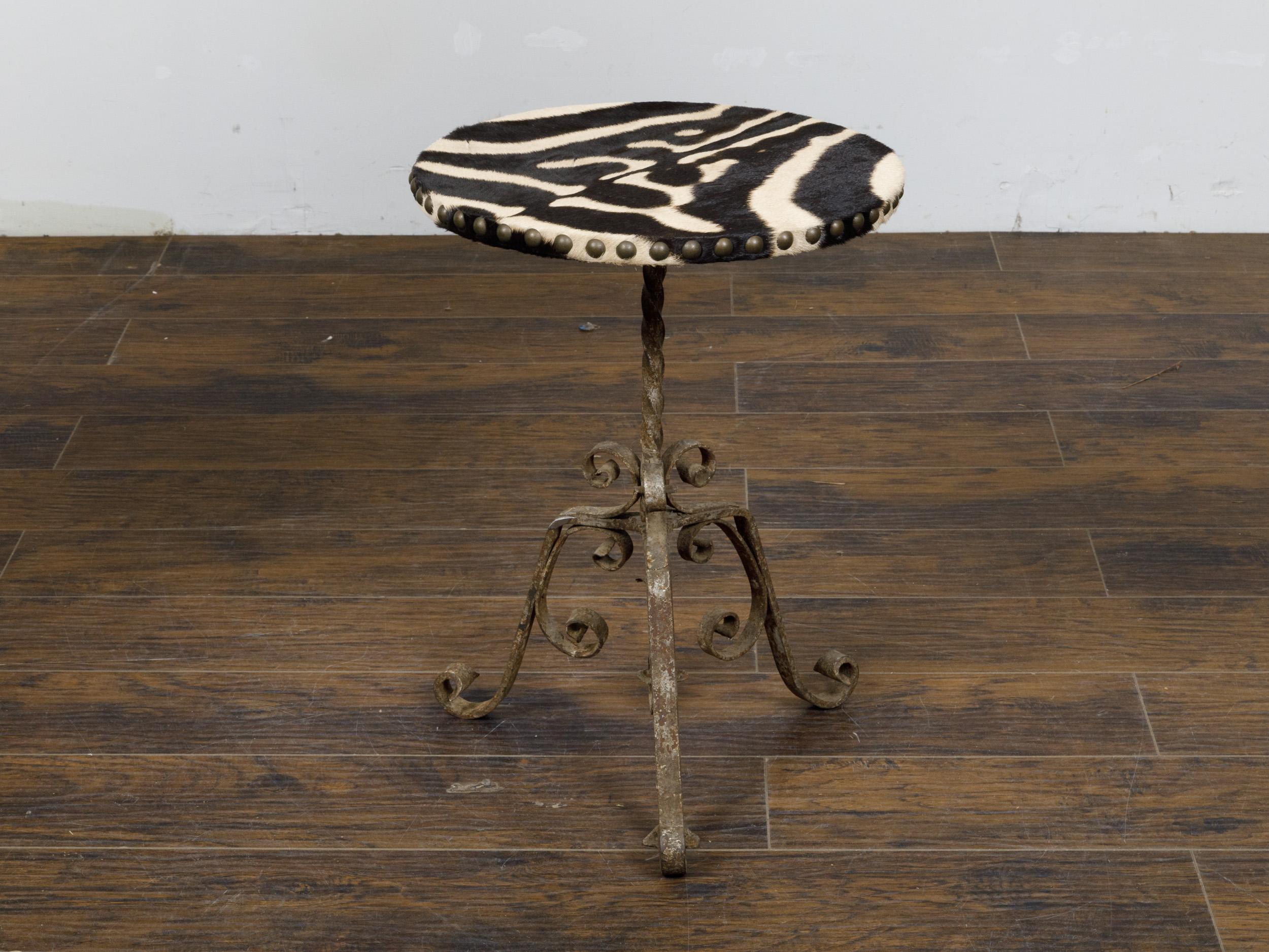 A French wrought-iron guéridon side table from circa 1920 with circular zebra hide top and scrolling tripod base. This exquisite French wrought iron guéridon side table from circa 1920 is a splendid blend of rustic charm and elegant design, making