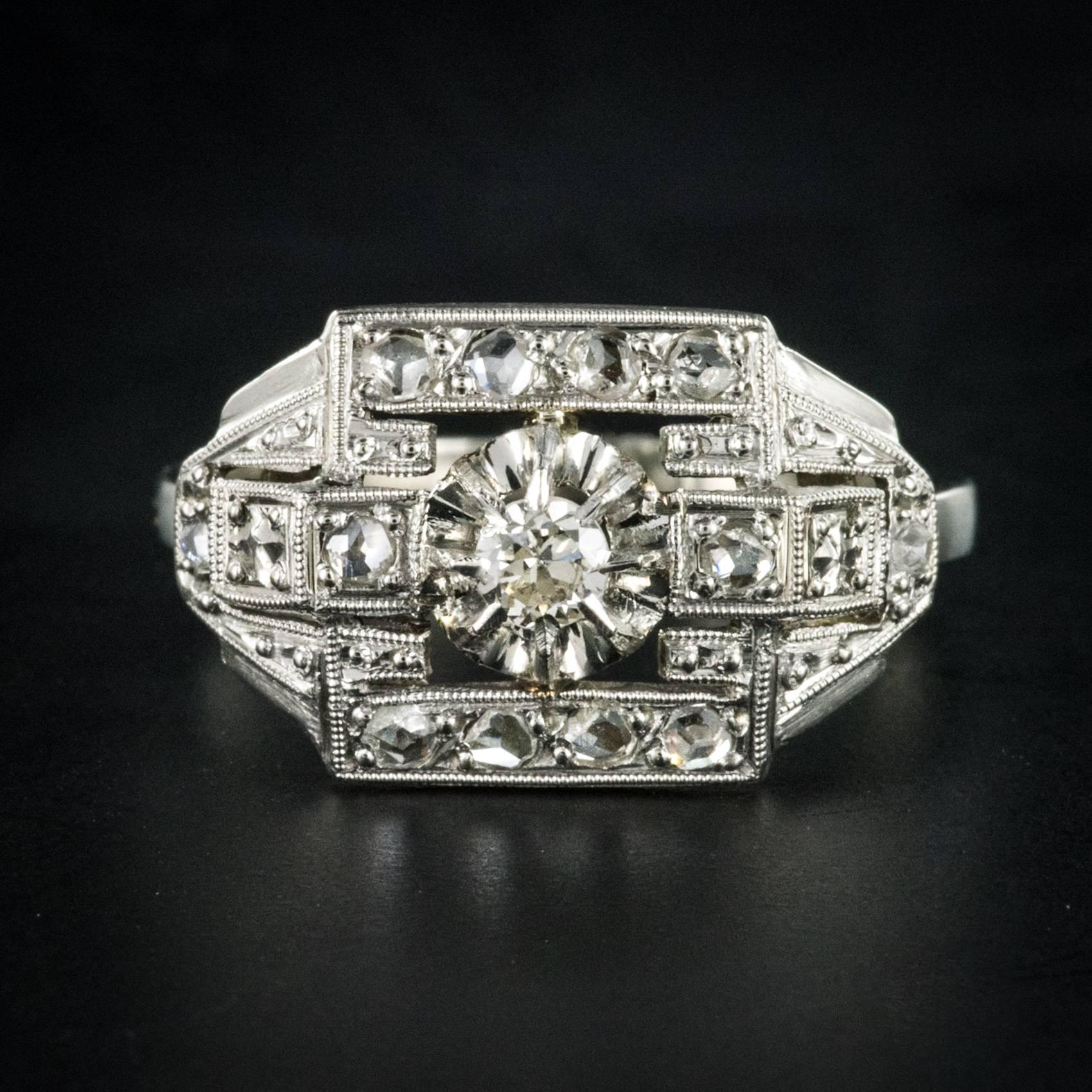 Ring in 18 karats white gold, eagle's head hallmark, and platinum dog's head hallmark.
French Art Deco ring, it is set with claws of a brilliant-cut diamond on a geometric openwork and set with rose-cut diamonds.
Weight of the central diamond: 0.12