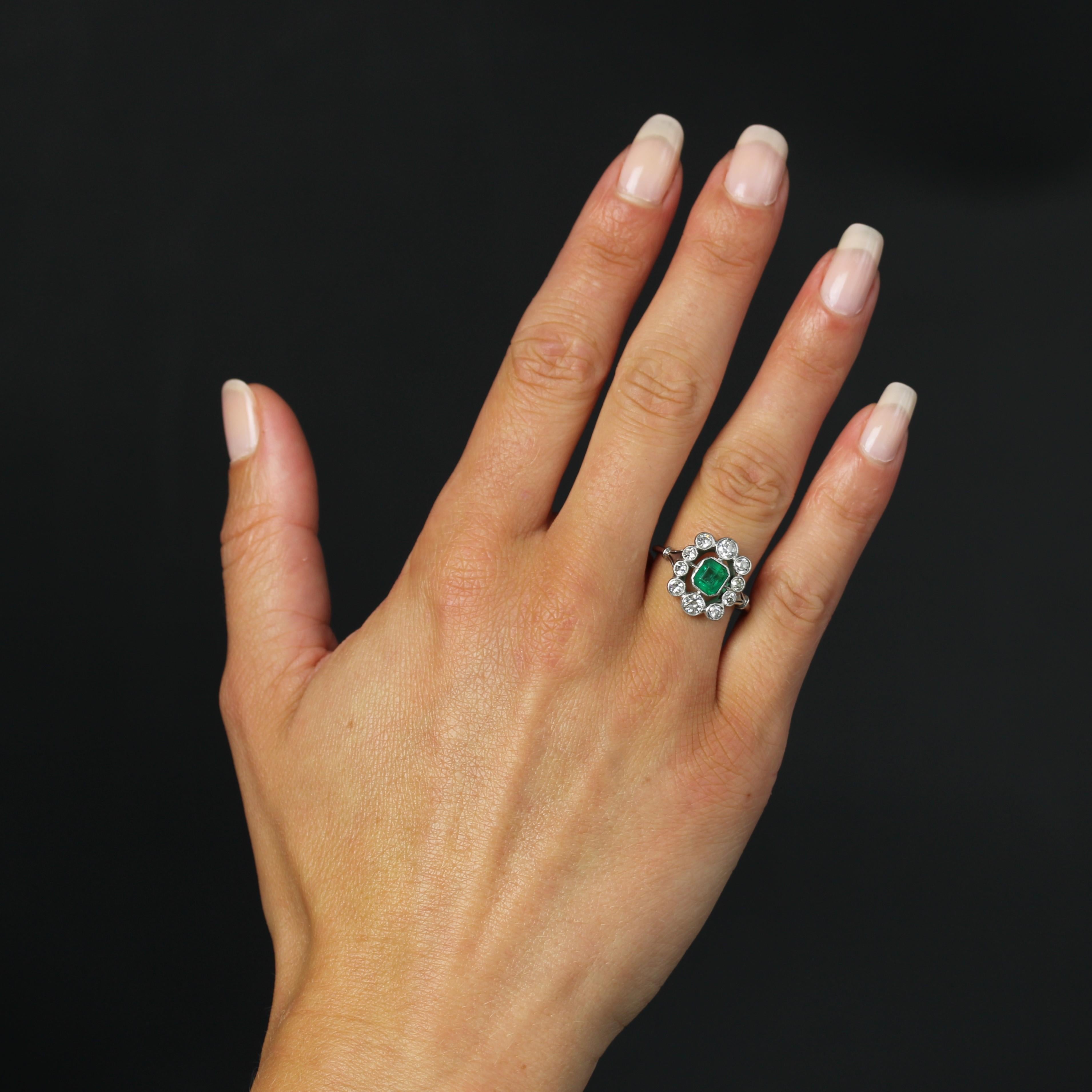 Ring in platinum, dog head hallmark.
Elegant antique ring with a very flat setting, featuring a central millegrain emerald in a setting of millegrain brilliant-cut diamonds. The corbeille is delicately openworked, and the start of the ring is formed