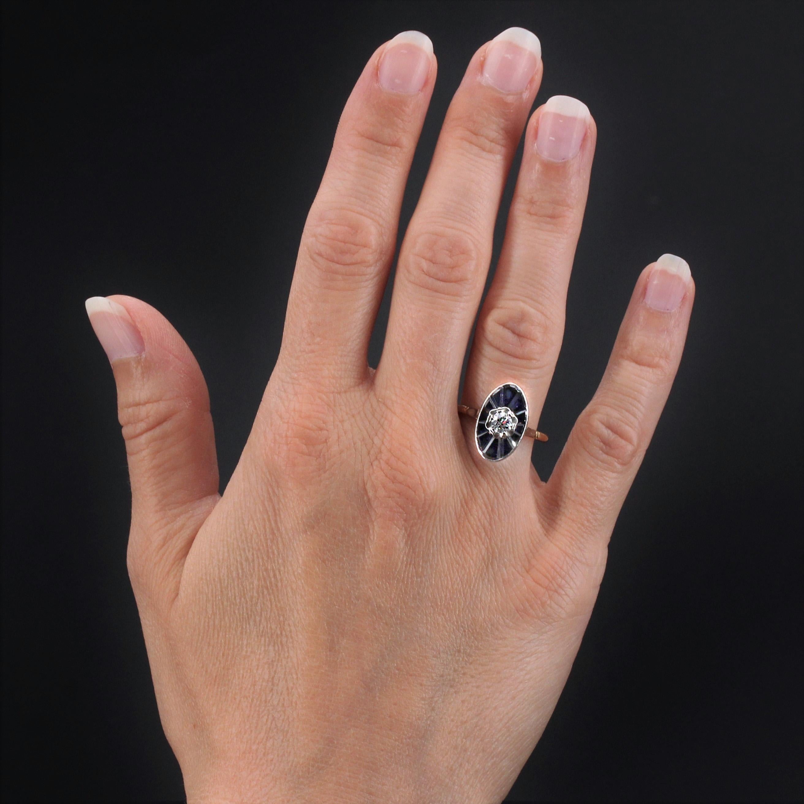 Ring aus 18 Karat Gelb- und Weißgold, Adlerkopfpunze.
Reizvoller antiker Ring, dessen Fassung in Form eines Schiffchens mit einem Diamanten im Brillantschliff in der Mitte einer Verzierung aus kalibrierten Synthesesasaphiren verziert ist. Der Korb