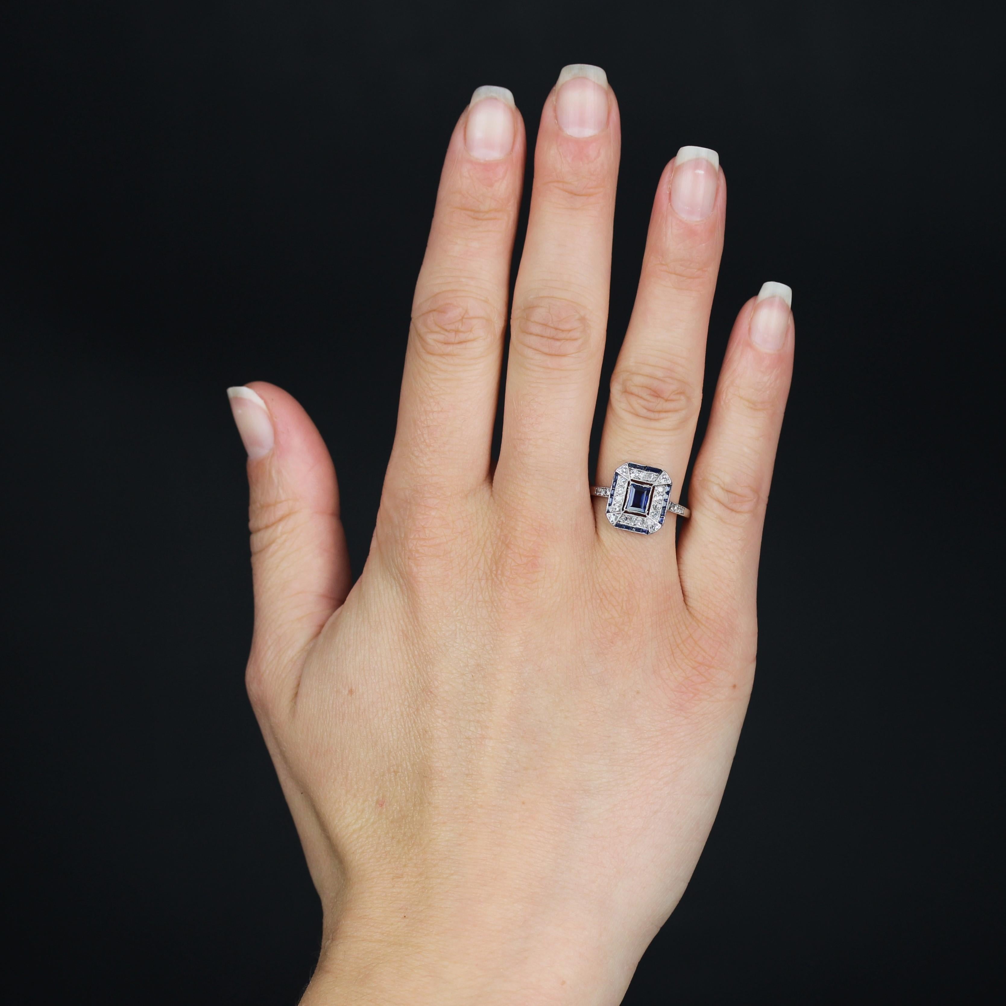Ring aus Platin, Hundekopfpunze.
Dieser authentische Art-déco-Ring liegt sehr flach am Finger und ist mit Diamanten im Antikschliff, kalibrierten Saphiren und einem rechteckigen Saphir in der Mitte besetzt. Auf beiden Seiten des Kopfes, am Anfang